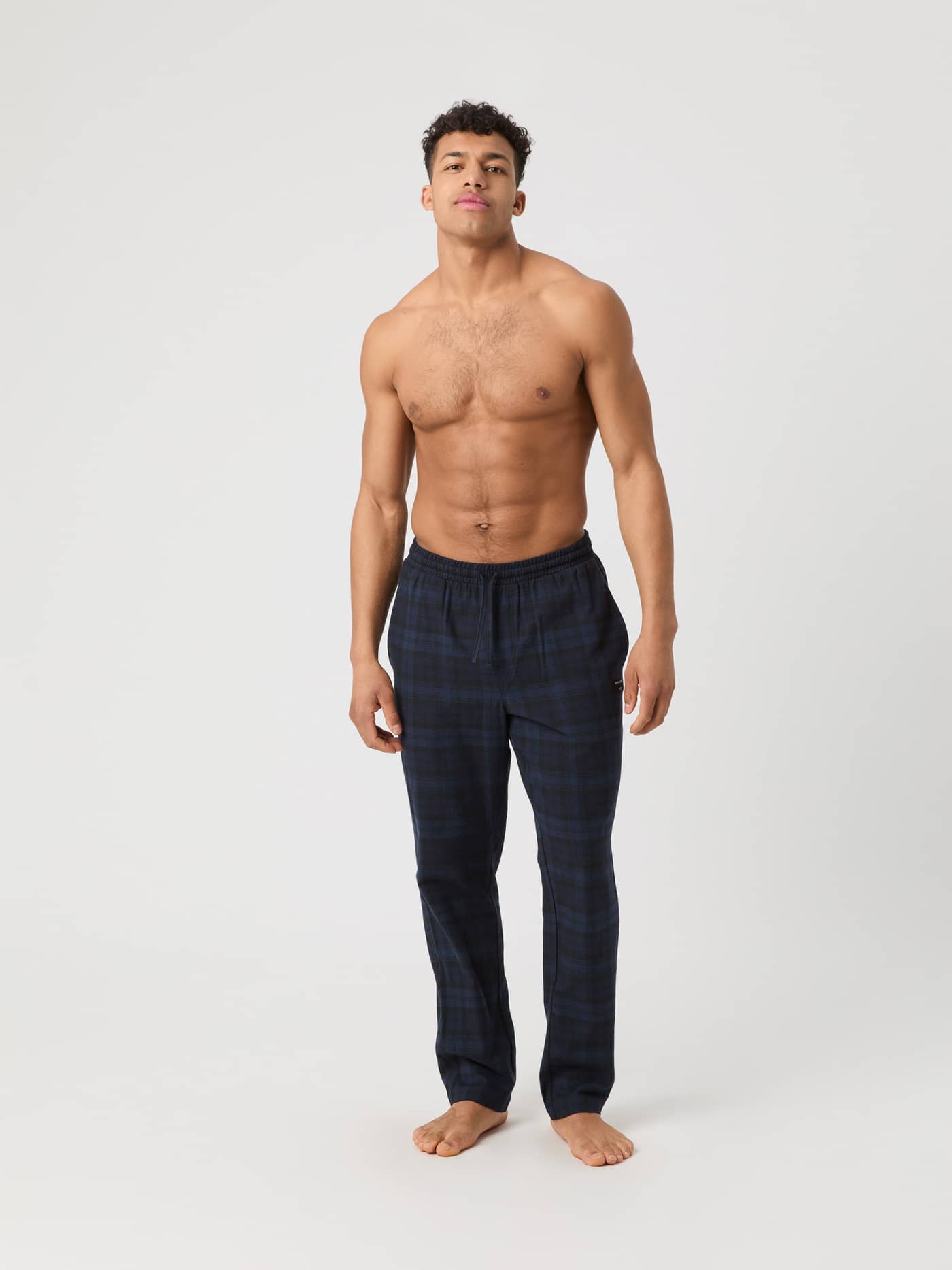 Male model wearing the Björn Borg Core Flannel Pyjama Pants in a dark blue tartan pattern, seen from the front. - Image 1