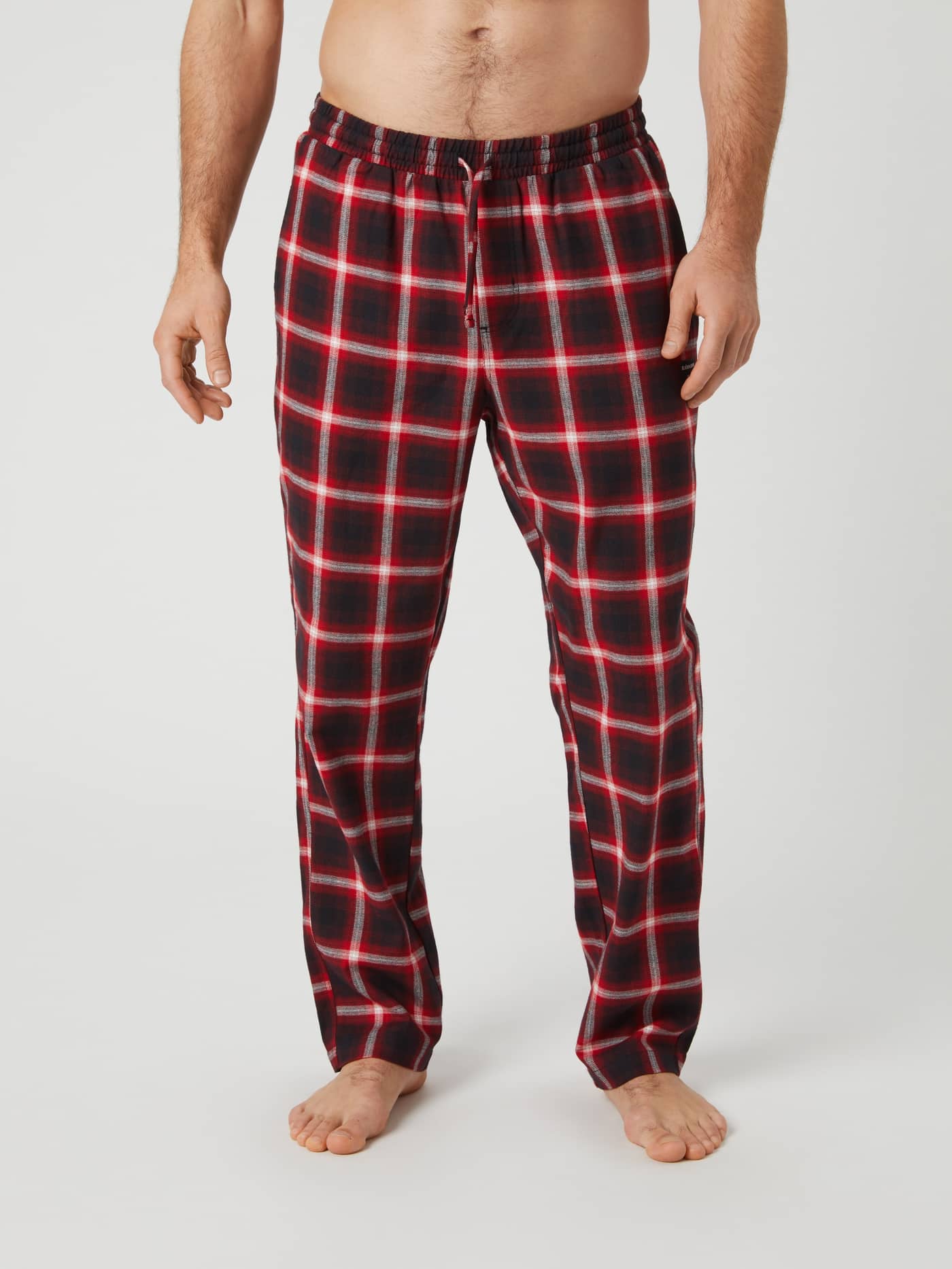 Front view of a man wearing Björn Borg Core Flannel Pyjama Pants in a red and black lumber check pattern. - Image 1