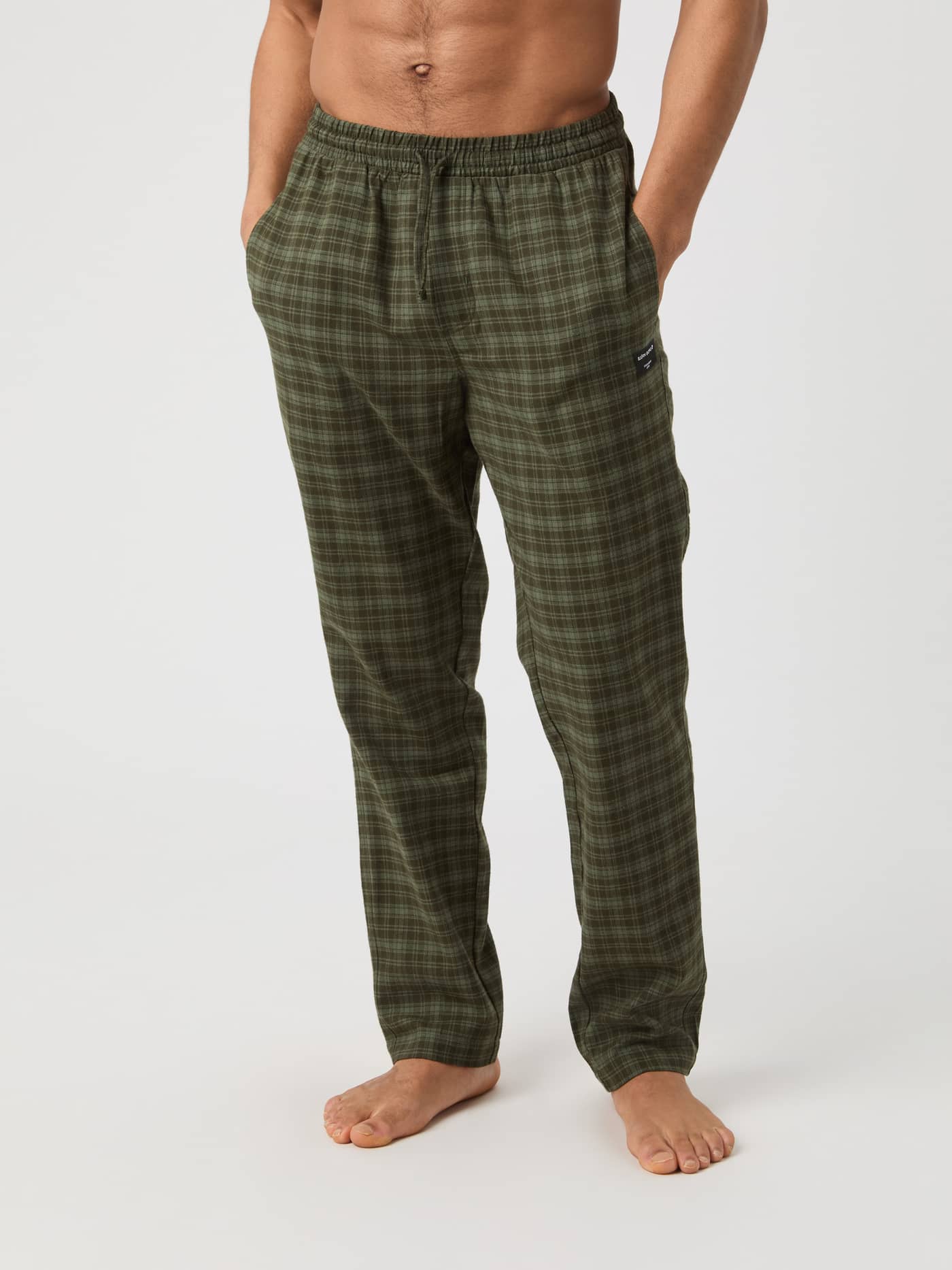 Front view of a male model wearing the Core Flannel Pyjama Pants in a green checked pattern. - Image 1