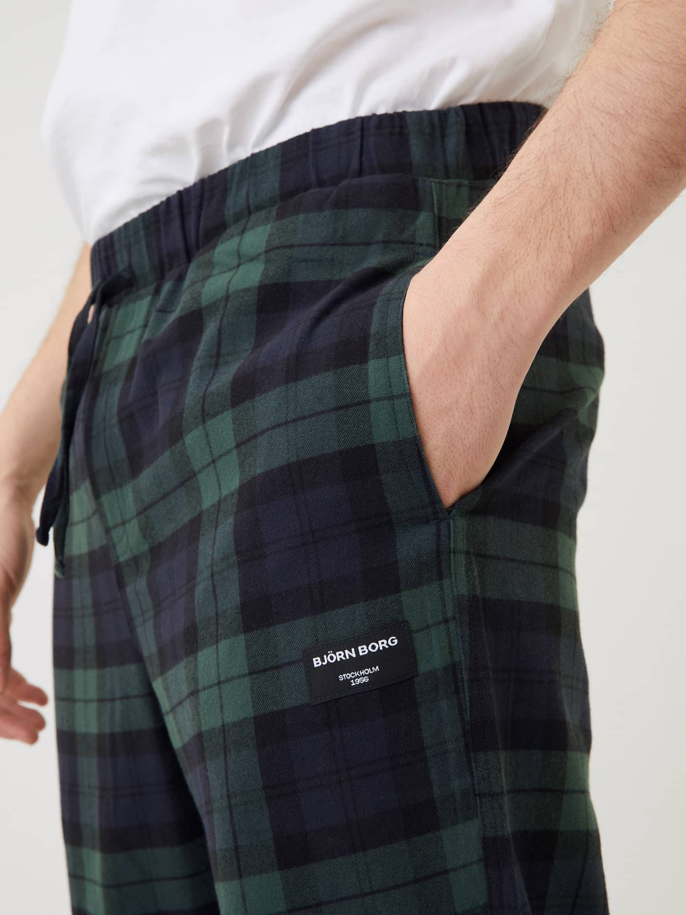 Close-up of a man wearing the Björn Borg Core Flannel Pyjama Pants in green and navy tartan, with his hand in the pocket. - Image 3