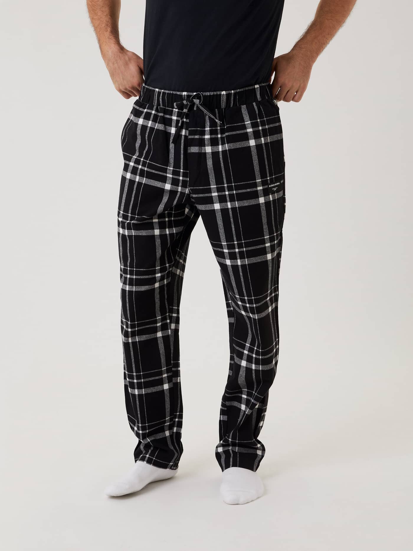 Vooraanzicht van een man in de zwart-witte Core Pyjama Pants van zacht flanel met een ruitpatroon. - Image 2