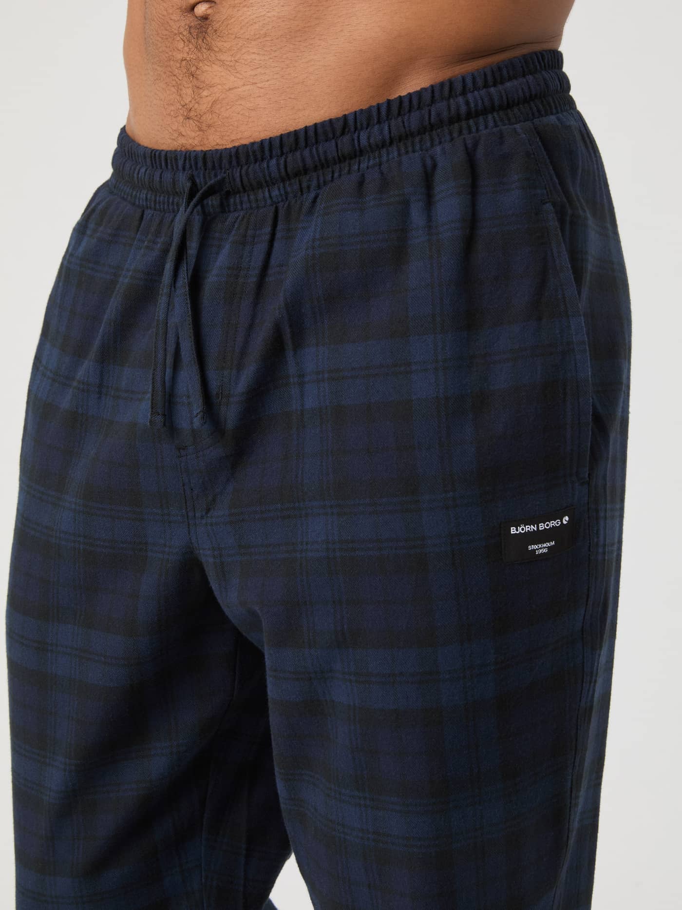 Close-up on a model wearing Björn Borg Core Flannel Pyjama Pants in navy tartan, showing the elastic waist and drawstring. - Image 4