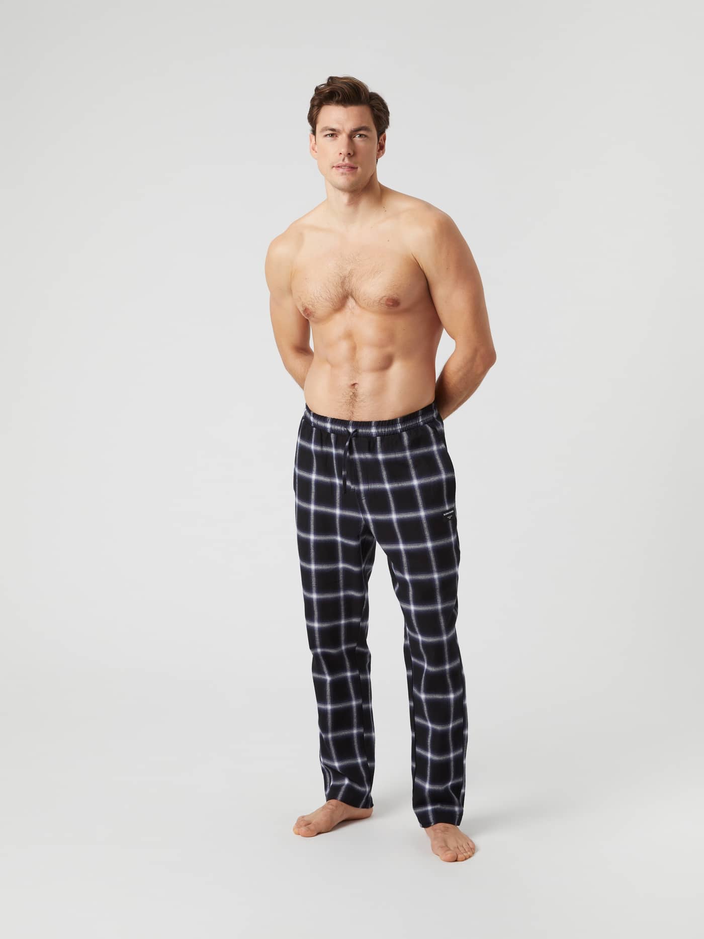 Front view of a model wearing the Björn Borg Core Flannel Pyjama Pants in a black and white lumber check pattern. - Image 1