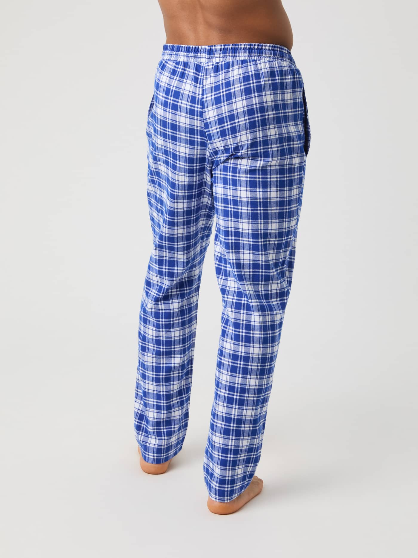 Back view of a model wearing the Core Flannel Pyjama Pants in a blue and white check pattern. - Image 3