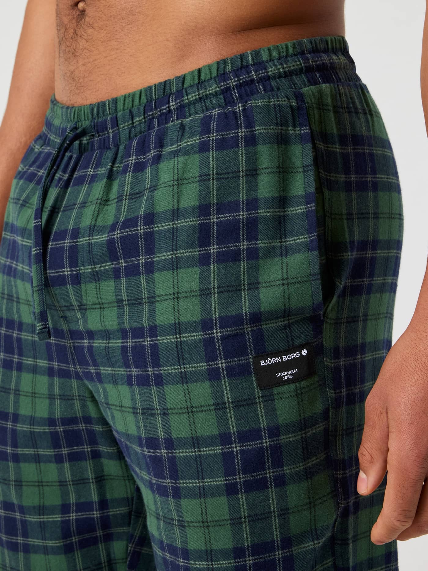Detailed side view of the Björn Borg Core Flannel Pyjama Pants in Forest Tartan 7 (Green) showing the pocket and logo patch. - Image 4