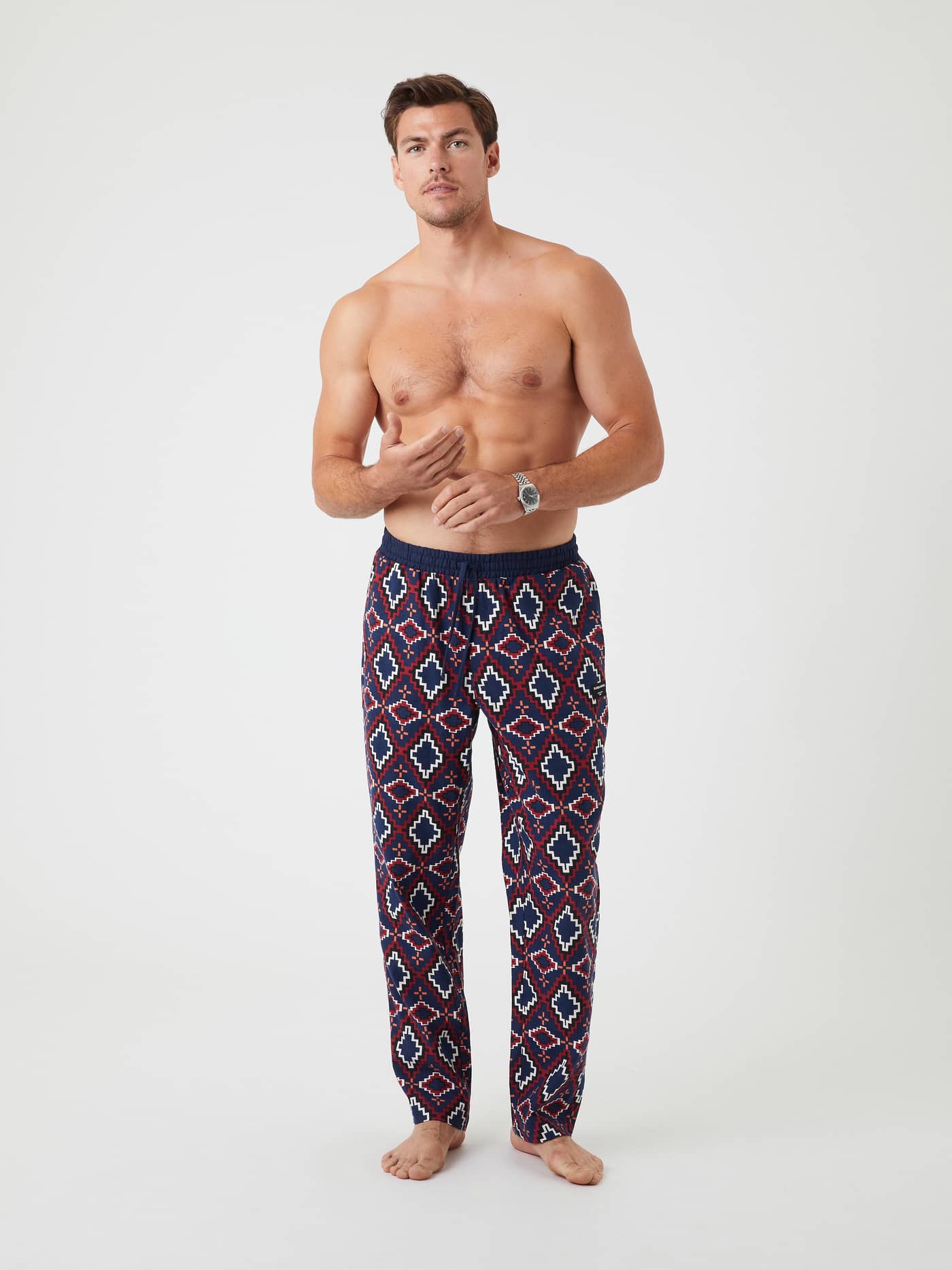 Front view of a male model wearing the multi-colored BB Tribe print Core Flannel Pyjama Pants. - Image 1