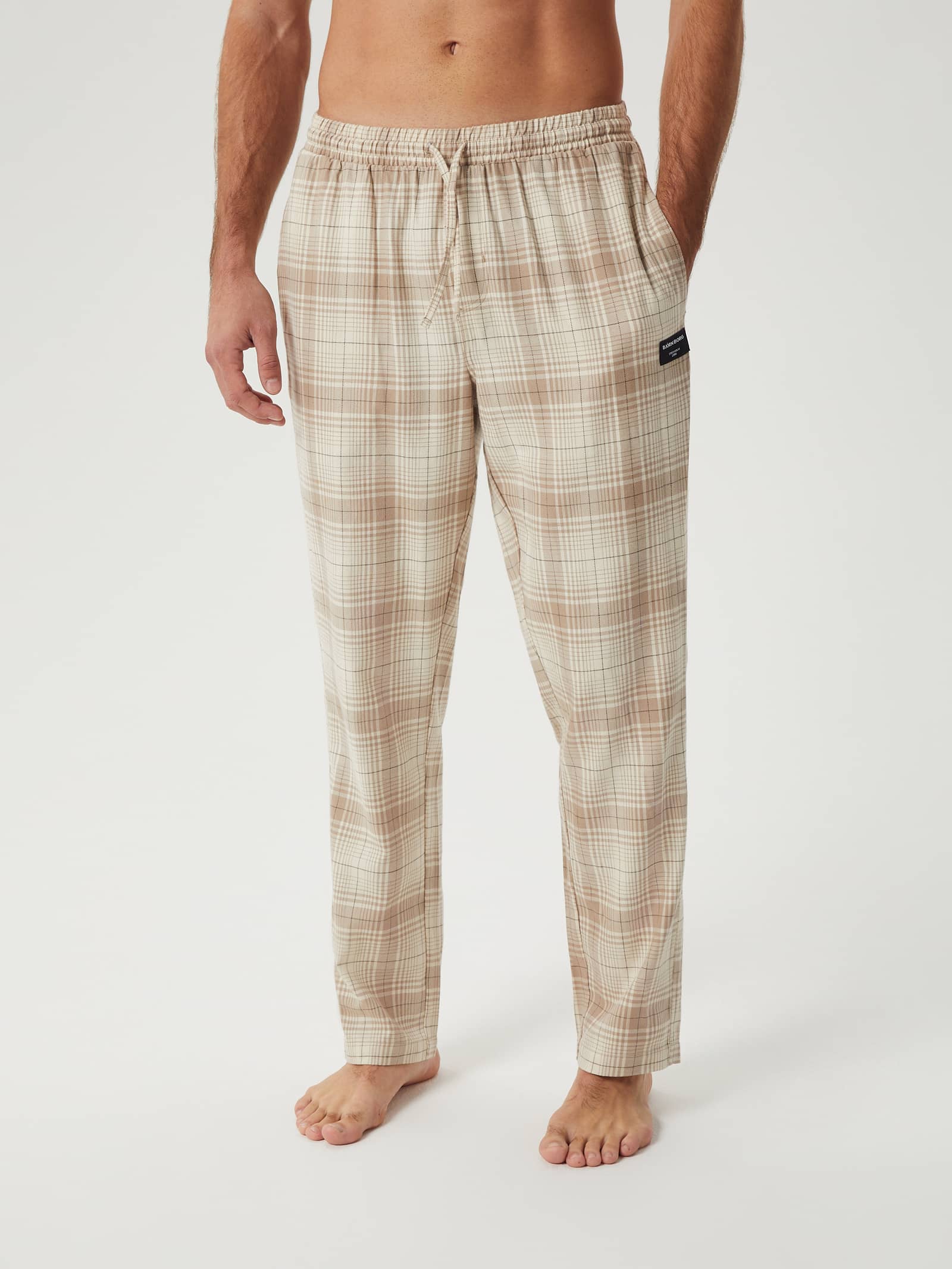 Front view of a model wearing the Björn Borg Core Flannel Pyjama Pants in a beige check pattern. - Image 1