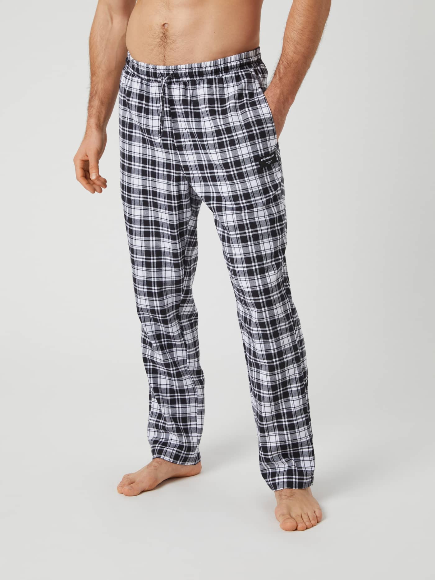 Front view of a model wearing the Björn Borg Core Flannel Pyjama Pants in a black and white checkered pattern. - Image 1