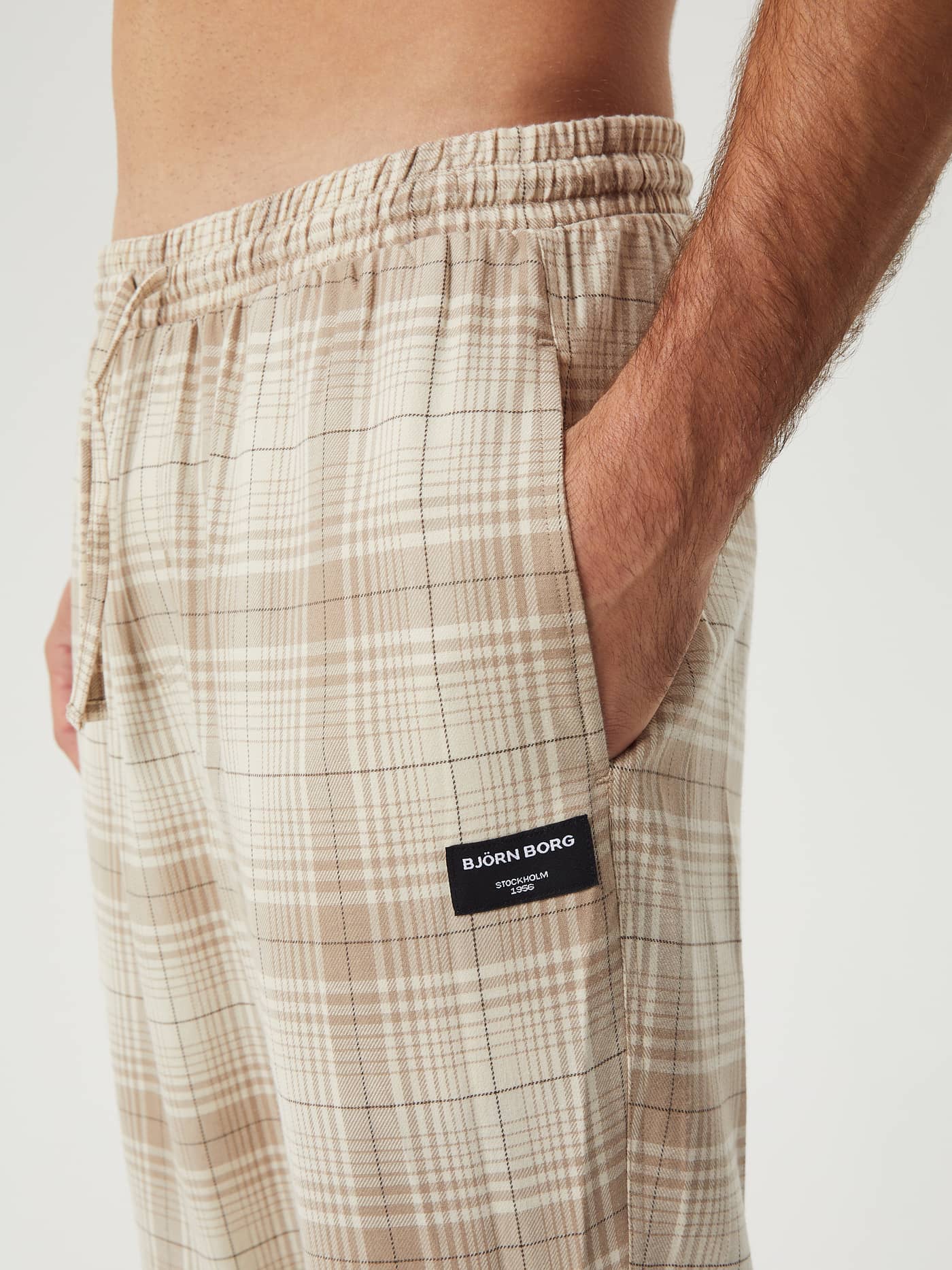 Close-up of the beige plaid Core Flannel Pyjama Pants, showing the side pocket, elastic waistband, and Björn Borg logo patch. - Image 4