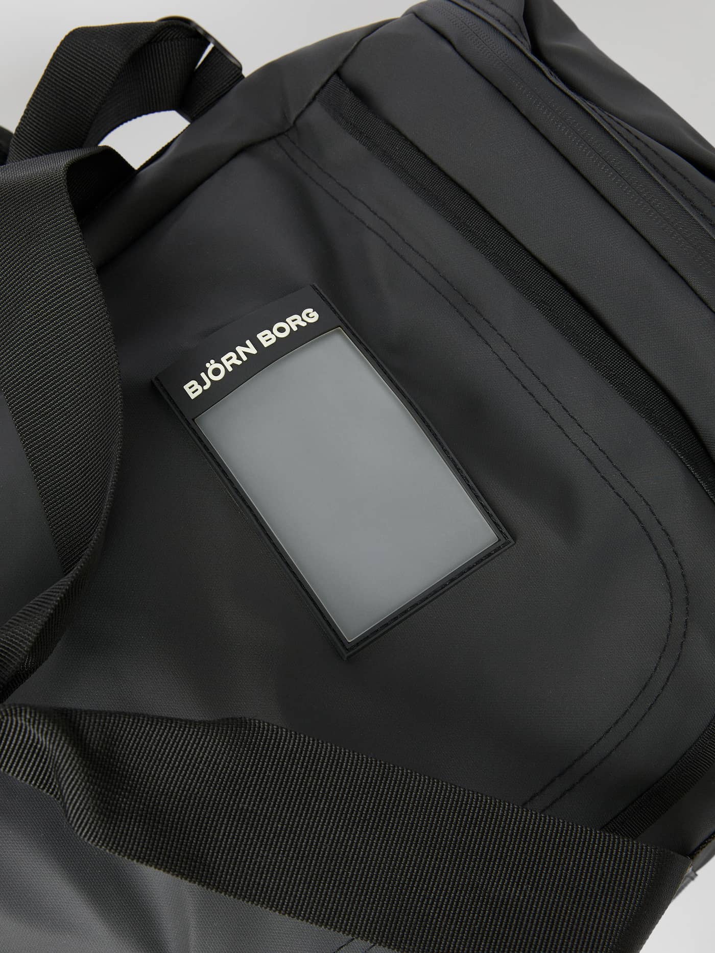 Close-up of the black BORG DUFFLE BAG 55L highlighting the integrated address tag and durable coated material. - Image 5