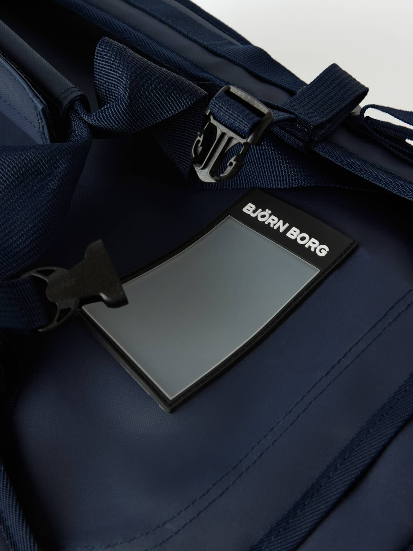 Nærbillede af adressemærkat på Borg Duffle Bag 55L i Night sky (Marineblå) i gummilignende materiale med hvidt logo. - Image 4