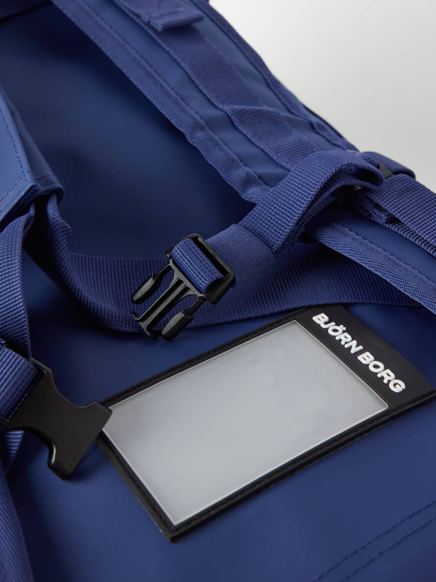 Close-up of the Estate Blue (Blue) Borg Duffle Bag 55L, featuring the black address tag with a white logo. - Image 2