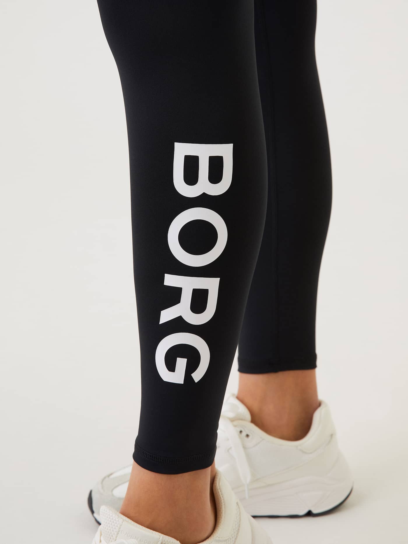 Detailed close-up of the white logo on the Borg Logo Tights in Black Beauty (Black), made from recycled training fabric. - Image 4