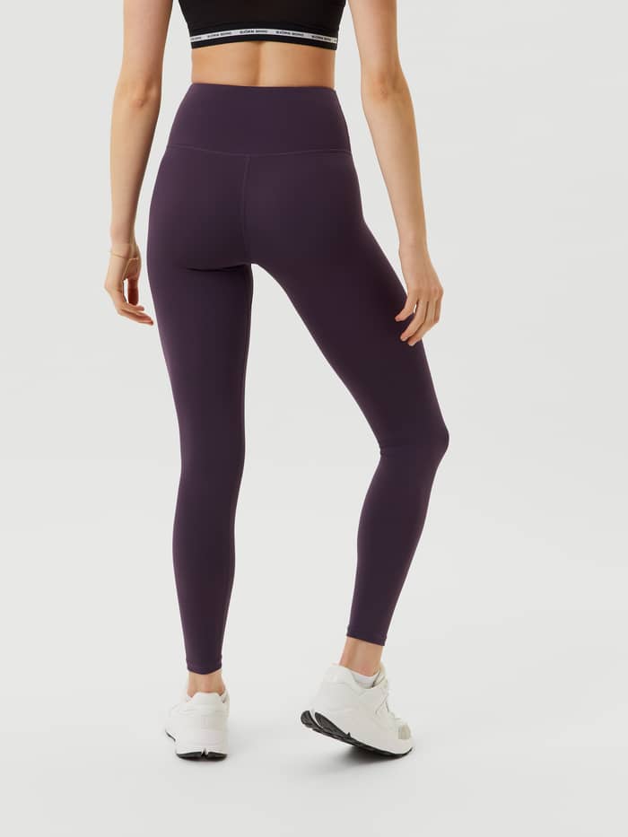 Back view of a model wearing high-waisted Björn Borg Logo Tights in Nightshade (Purple) with a white logo for training. - Image 3