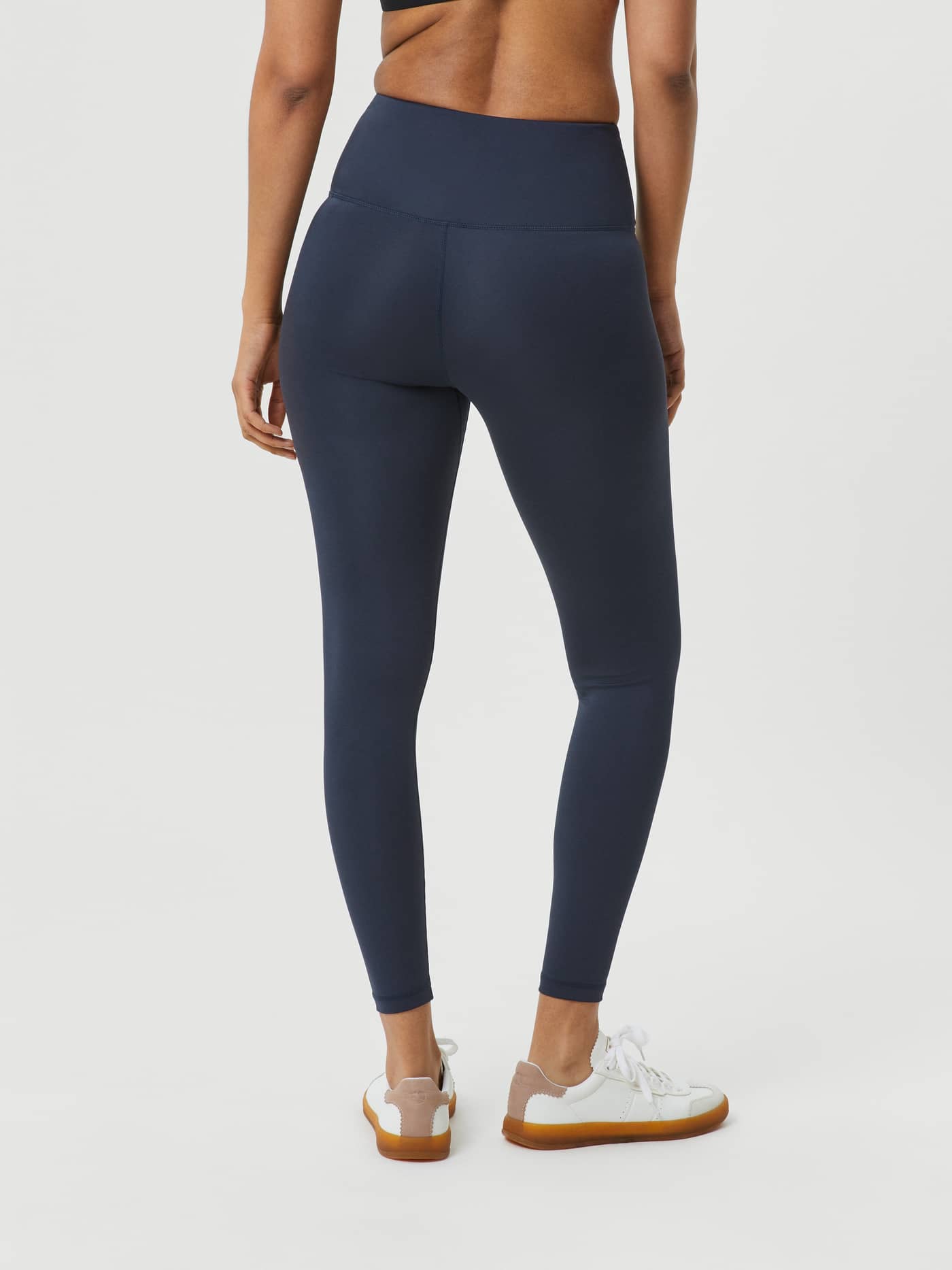 Back view of a woman wearing the full-length high-waist Björn Borg Logo Tights in Outerspace (Blue) for training. - Image 3