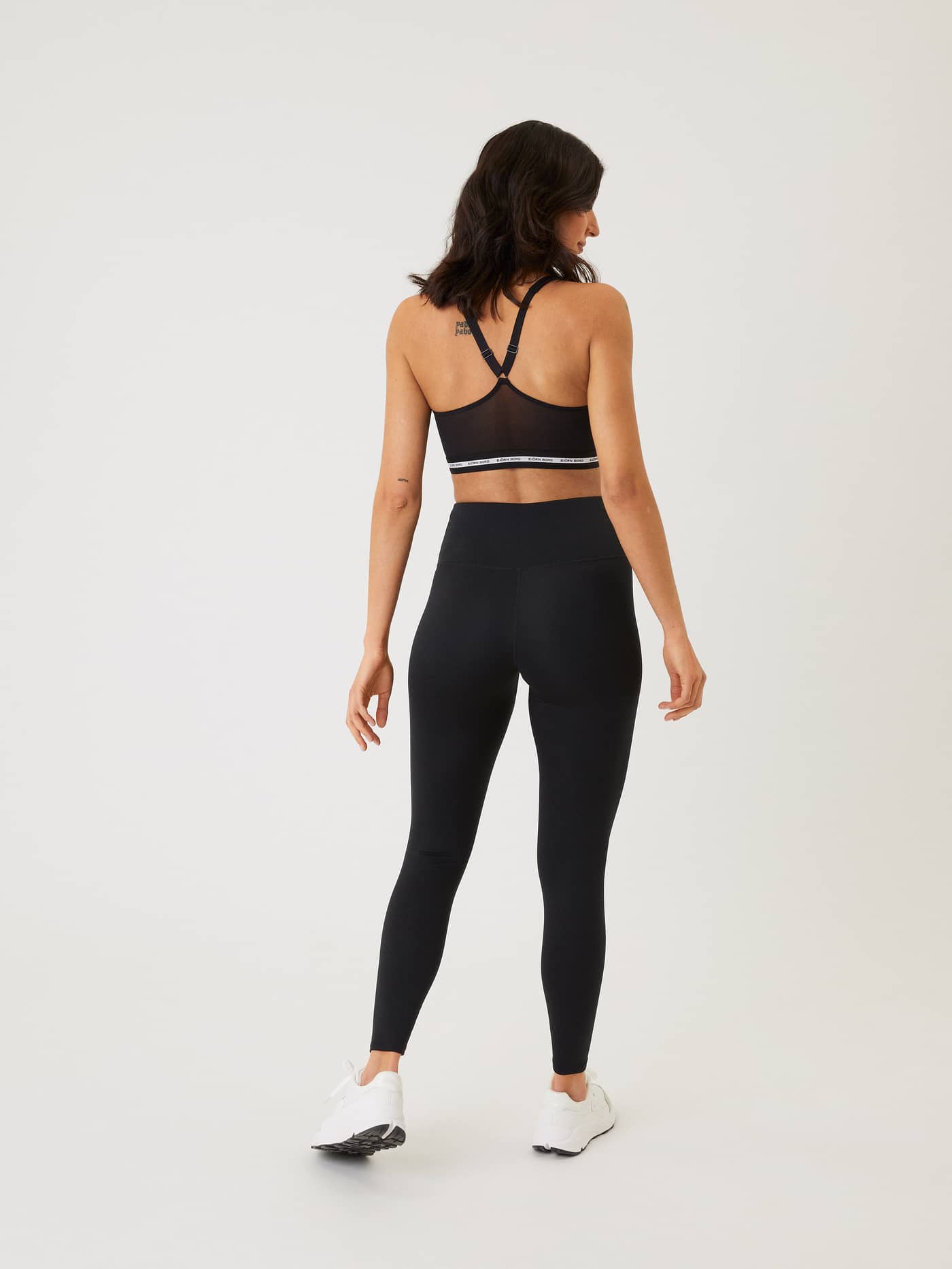 Back view of a model wearing high-waisted, full-length Björn Borg Logo Tights in Black Beauty (Black) for training. - Image 3