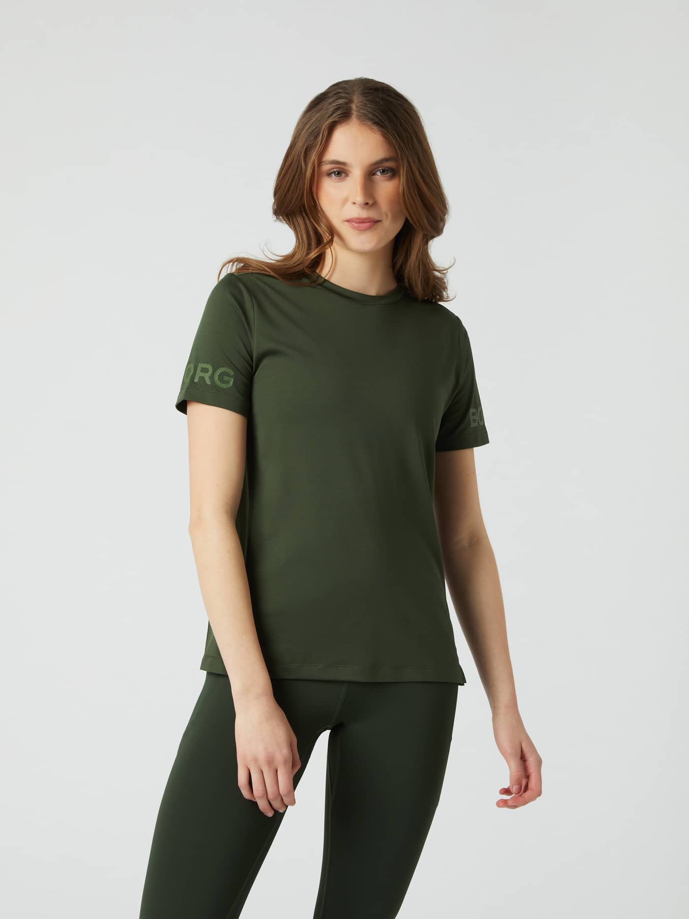 Front view of a woman wearing the Borg T-Shirt in Duffel Bag (Green), featuring iconic logos for a stylish training fit. - Image 1