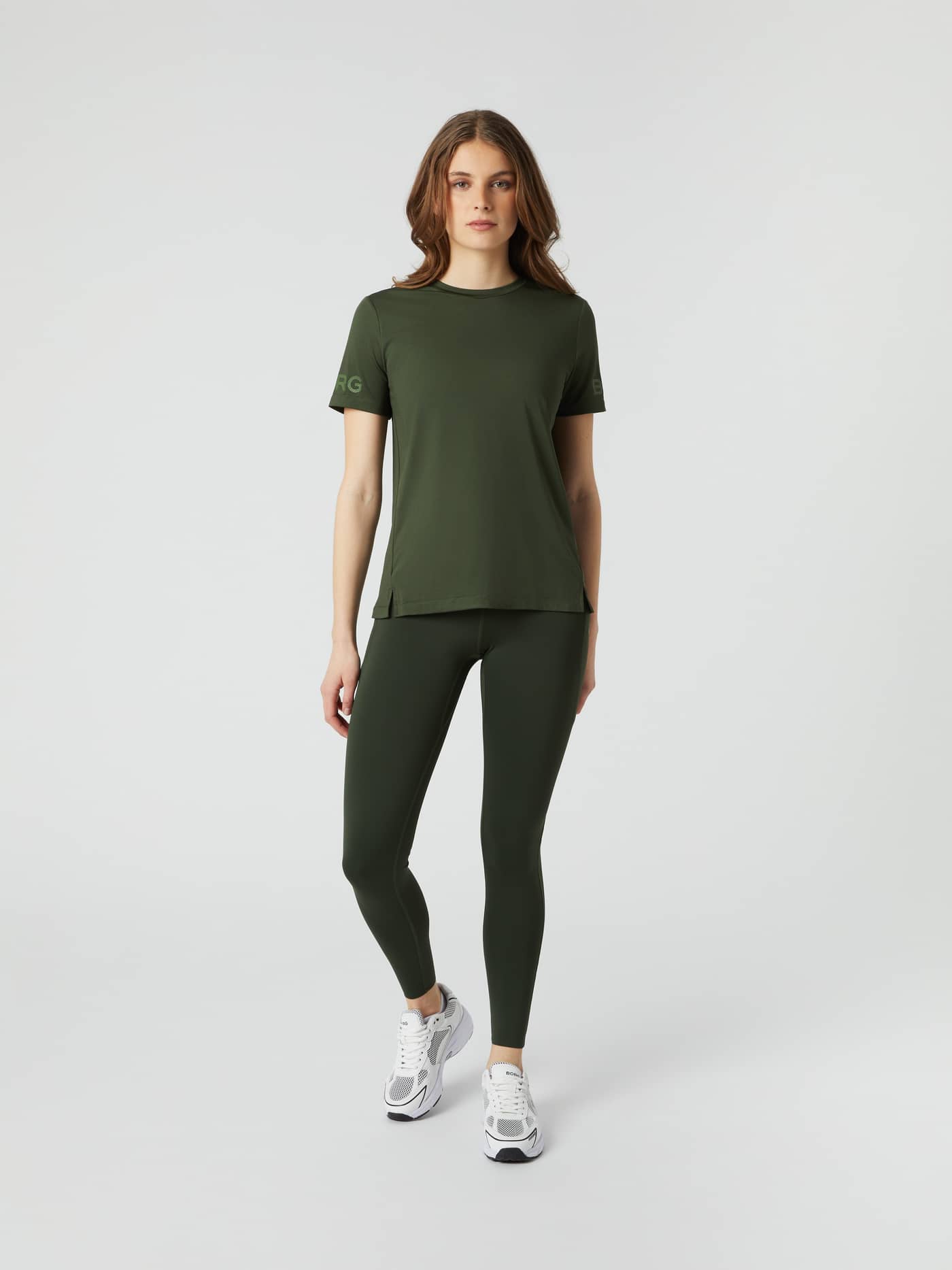 Full-body front view of a woman in the Duffel Bag (Green) Borg T-Shirt with a green logo, for performance training. - Image 3