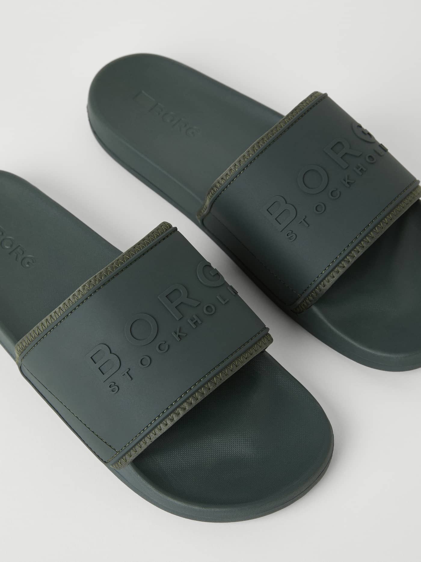 Close-up of the green Men's Sandal Romeo Sthlm Logo showcasing the tonal embossed logo on the durable TPU strap. - Image 2