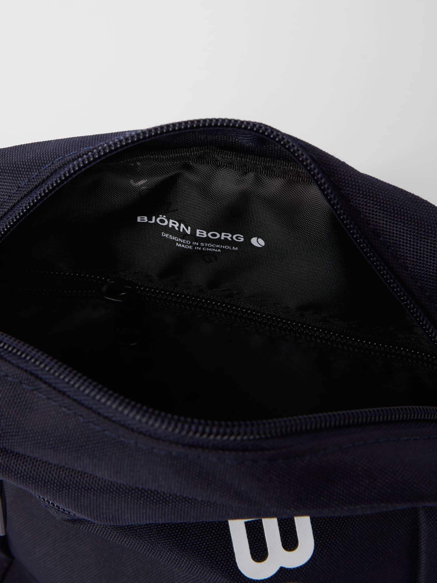 Binnenaanzicht van de polyester Core Crossover Bag 1,7L in Night Sky (Marineblauw) met ritsvak en wit logo. - Image 3