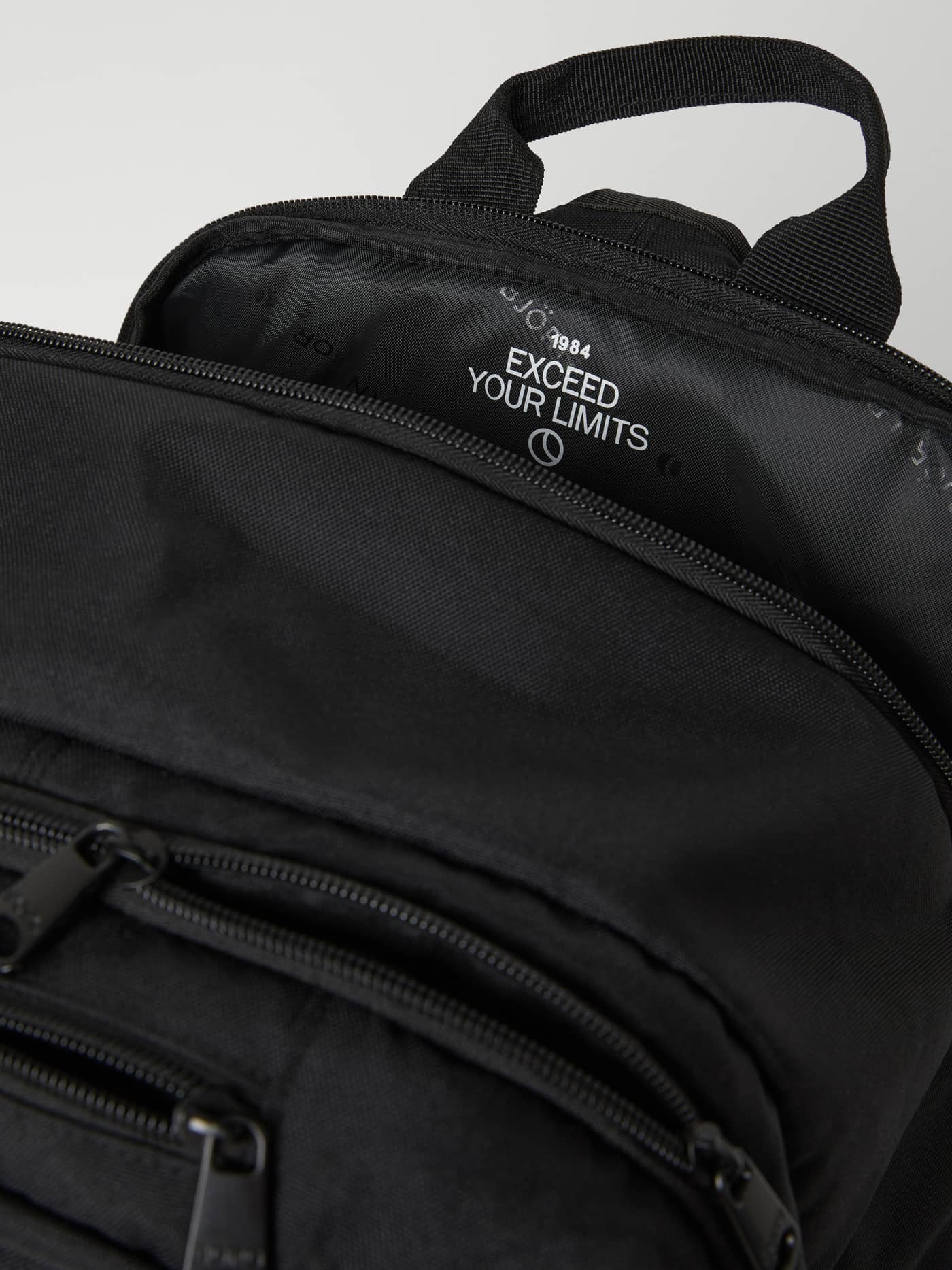 Vue intérieure détaillée du Core Curve Backpack 27L noir affichant le message blanc imprimé Exceed Your Limits. - Image 6