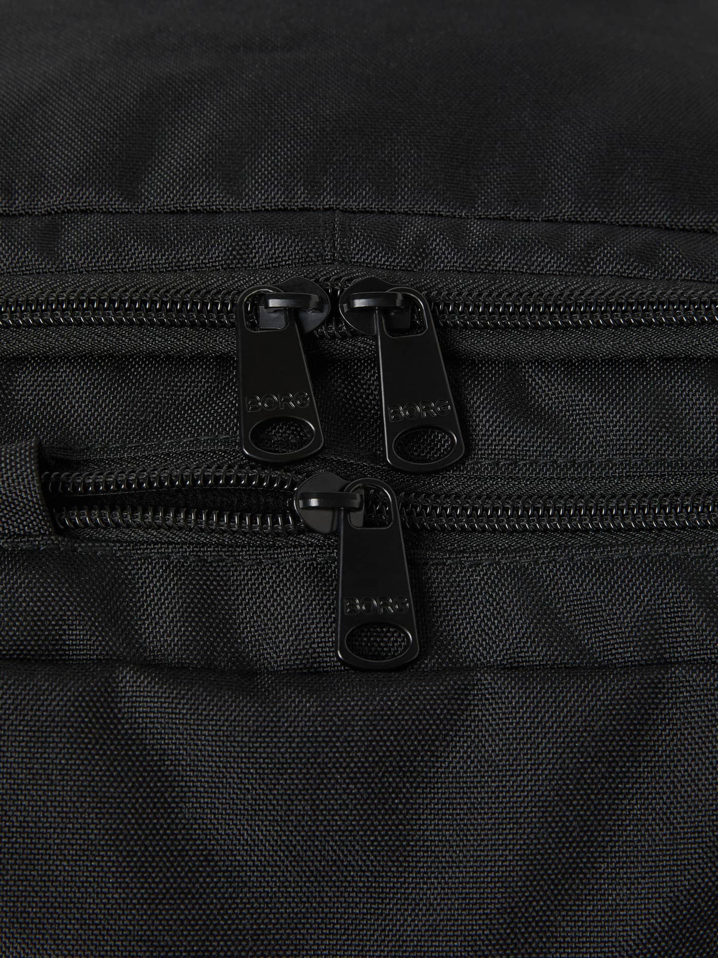 Gros plan sur les fermetures éclair noires et les logos embossés du Core Curve Backpack 27L en Black Beauty (Noir). - Image 4