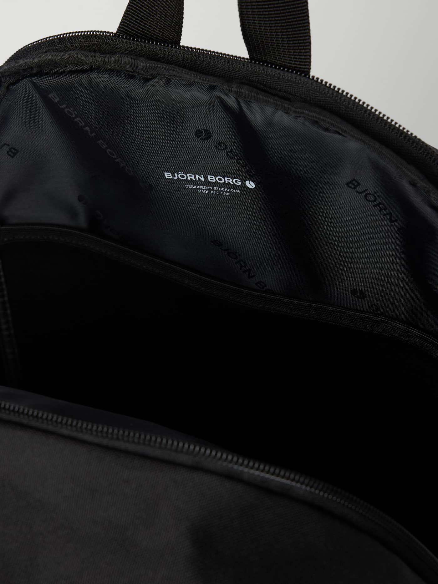 Innsiden av svart CORE ICONIC BACKPACK 17L med hvit logo og en polstret laptoplomme. - Image 3