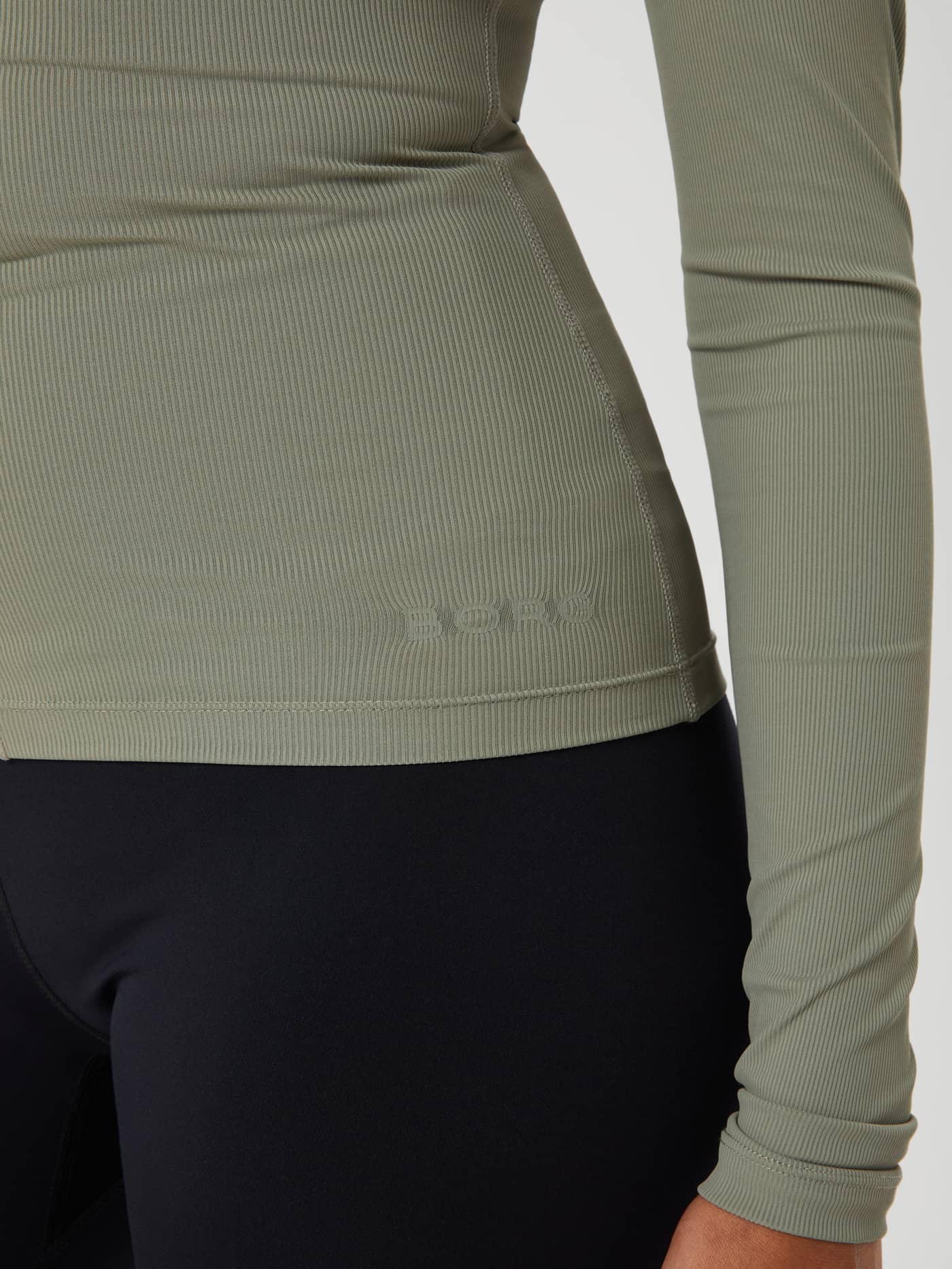 Close-up of the Studio Ballerina Long Sleeve training top in Vetiver (Green) showing the ribbed fabric and BORG logo. - Image 5