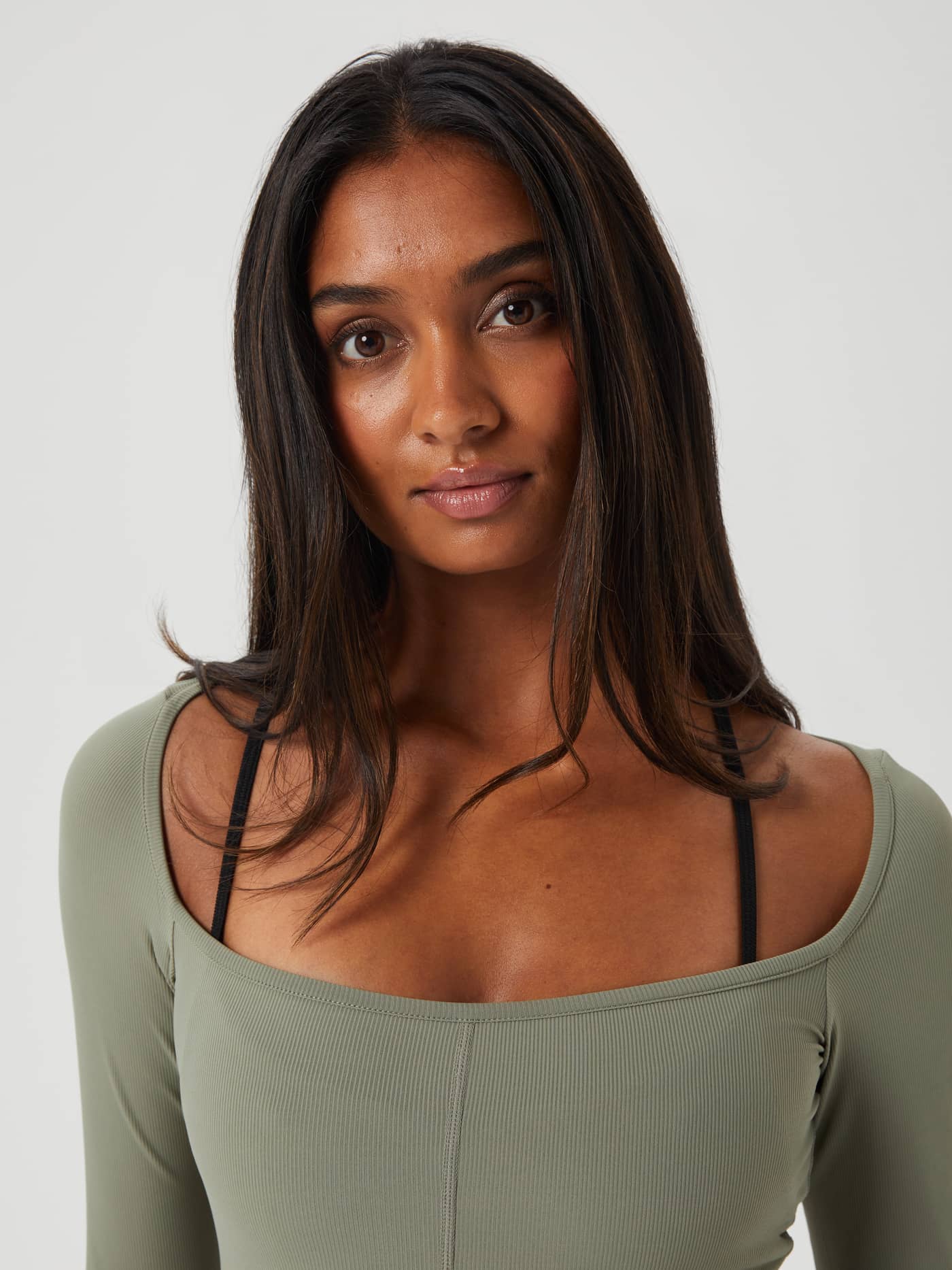 Close-up front view of a woman wearing the slim-fit Studio Ballerina Long Sleeve training top in Vetiver (Green). - Image 4