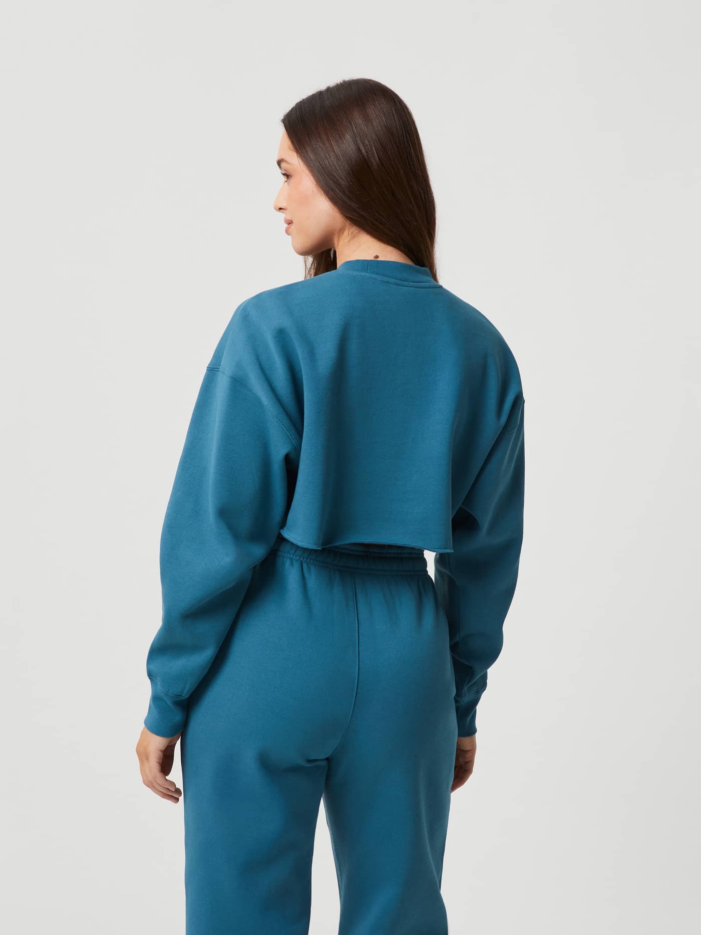 Back view of a woman wearing the Björn Borg Studio Oversized Cropped Crew in Mallard Blue (Blue) with an oversized fit. - Image 3