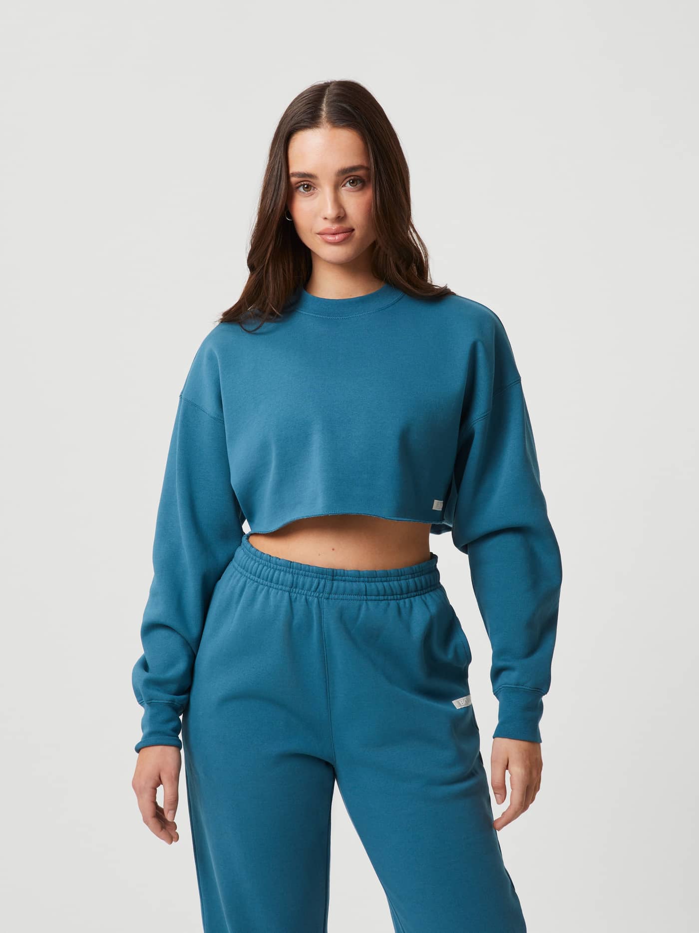 Front view of a model wearing the Björn Borg Studio Oversized Cropped Crew in Mallard Blue (Blue) with a stylish fit. - Image 2