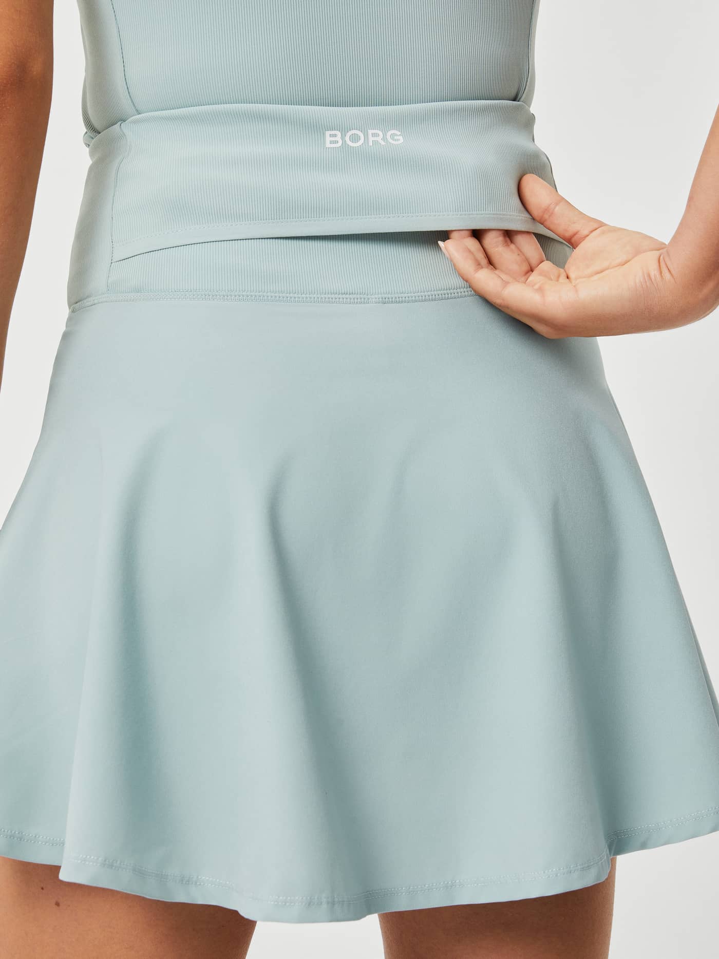 Ace Skirt Pocket i Gray Mist (Blå) sett bakfra, som fremhever hvit BORG-logo og den praktiske tennisballommen. - Image 4