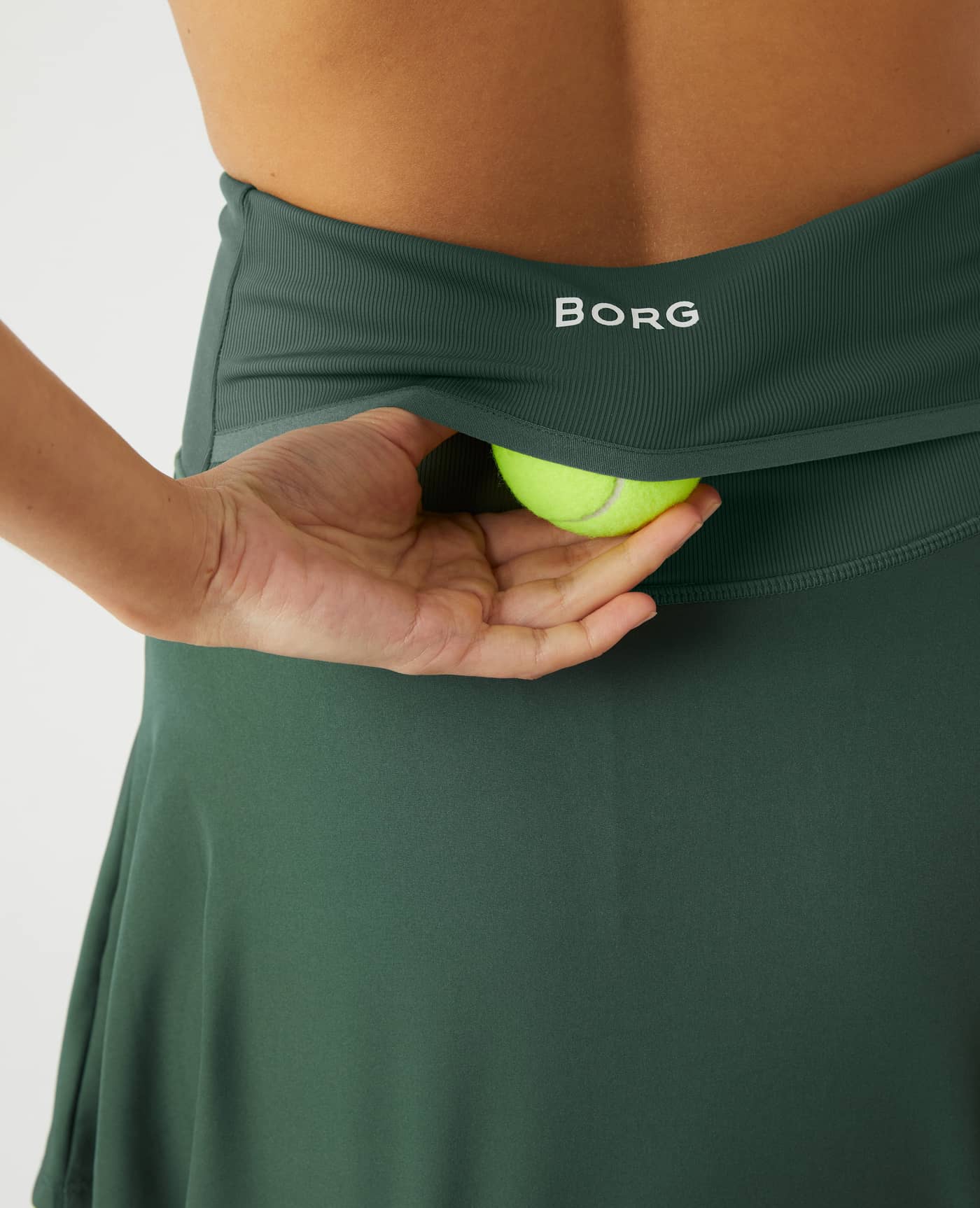 Close-up back view of the Ace Skirt Pocket in Cilantro (Green), highlighting the tennis ball pocket and white BORG logo. - Image 4