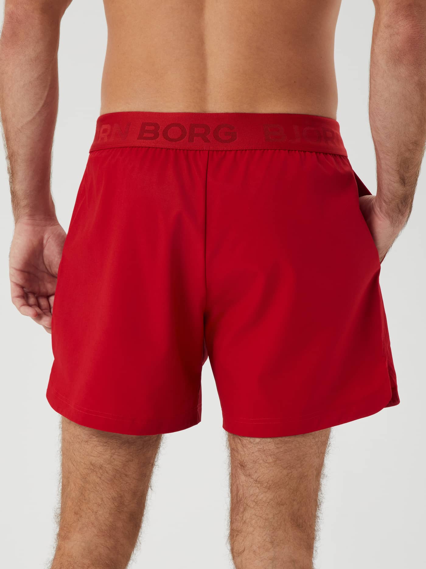 Back view of a man wearing the Björn Borg Ace Short Shorts in Samba (Red), functional training shorts for tennis. - Image 3