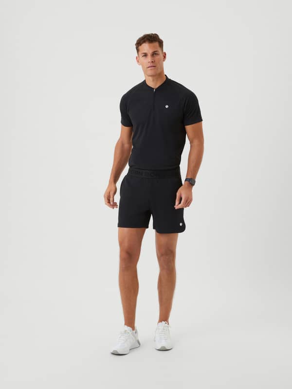 Full-body front view of a man in Björn Borg Ace Short Shorts in Black Beauty (Black) with a white logo for tennis training.