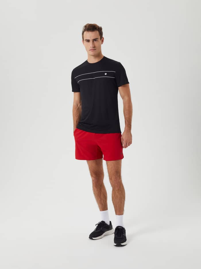 Full-body front view of a model wearing the Björn Borg Ace Short Shorts in Samba (Red) for tennis training.