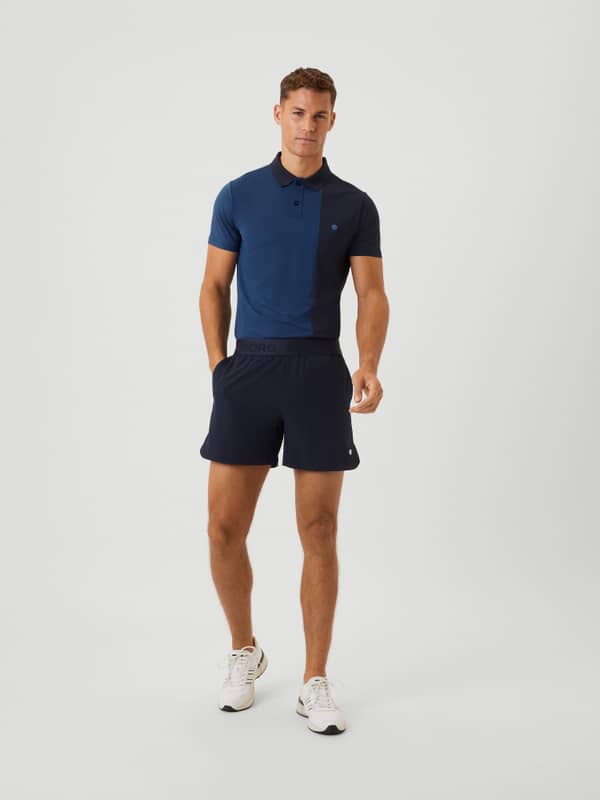 Full-body front view of a man wearing the Björn Borg Ace Short Shorts in Night Sky (Navy) for training and tennis.