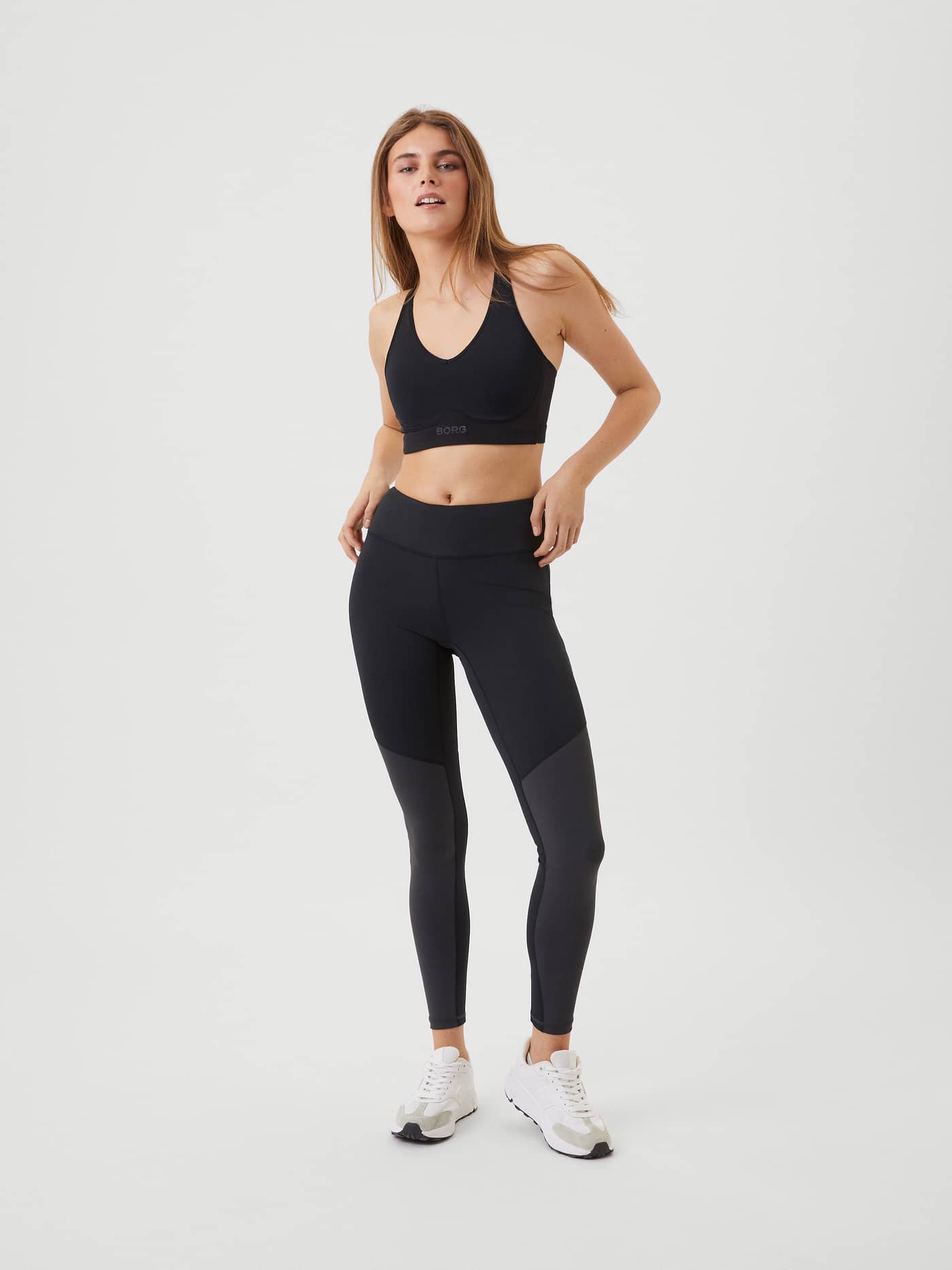 Full-body front view of a woman in the Black Beauty (Black) Borg Mid V Support with a tonal logo and a stylish training fit. - Image 3