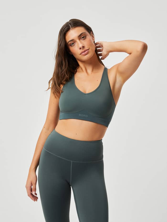 Modell framifrån i Borg Mid V Support i Urban Chic (Grön) för träning, med en BORG-logotyp i ton-i-ton.
