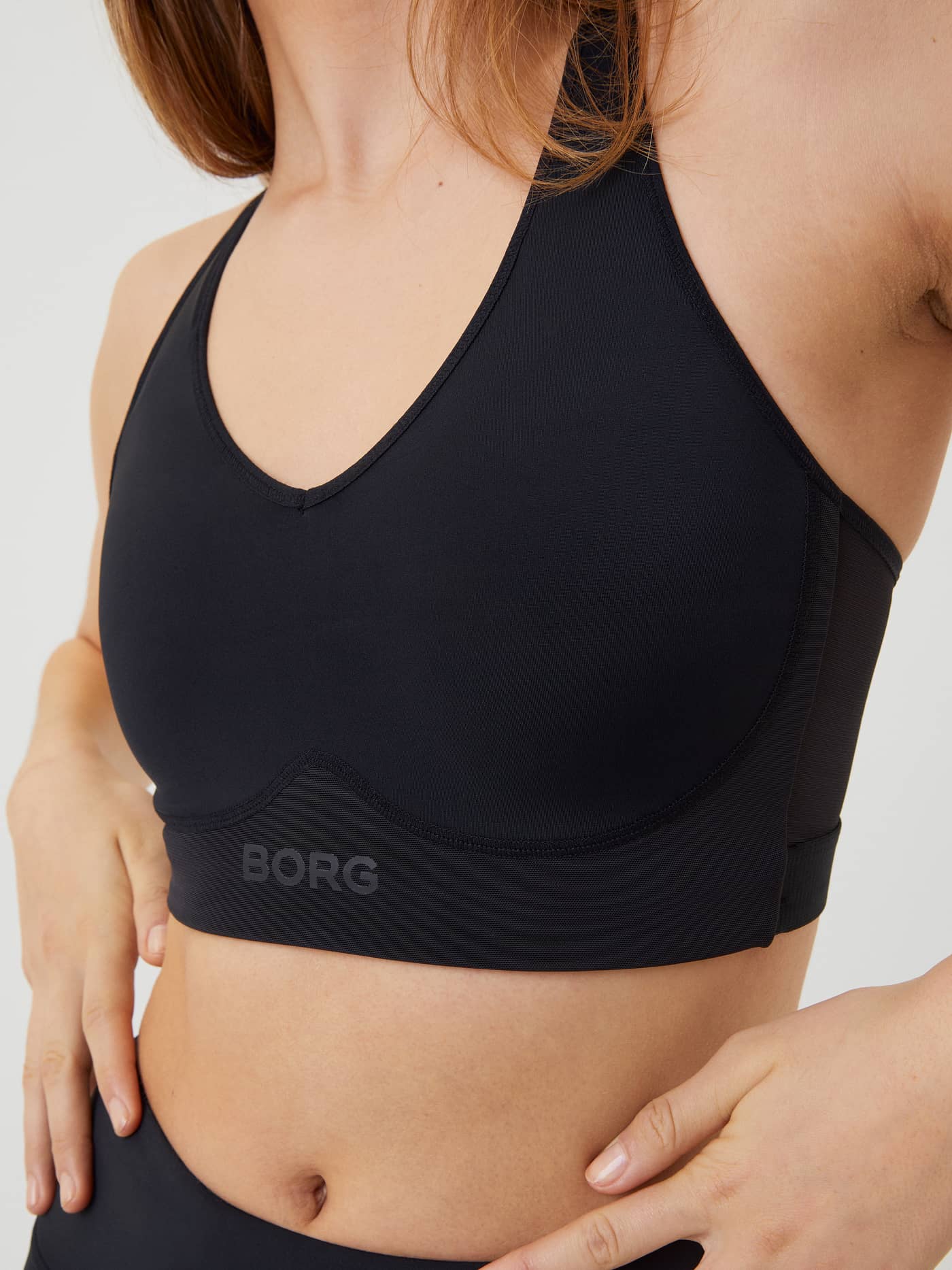 Close-up of the black Borg Mid V Support training bra featuring a tonal logo and a supportive, stylish fit. - Image 4
