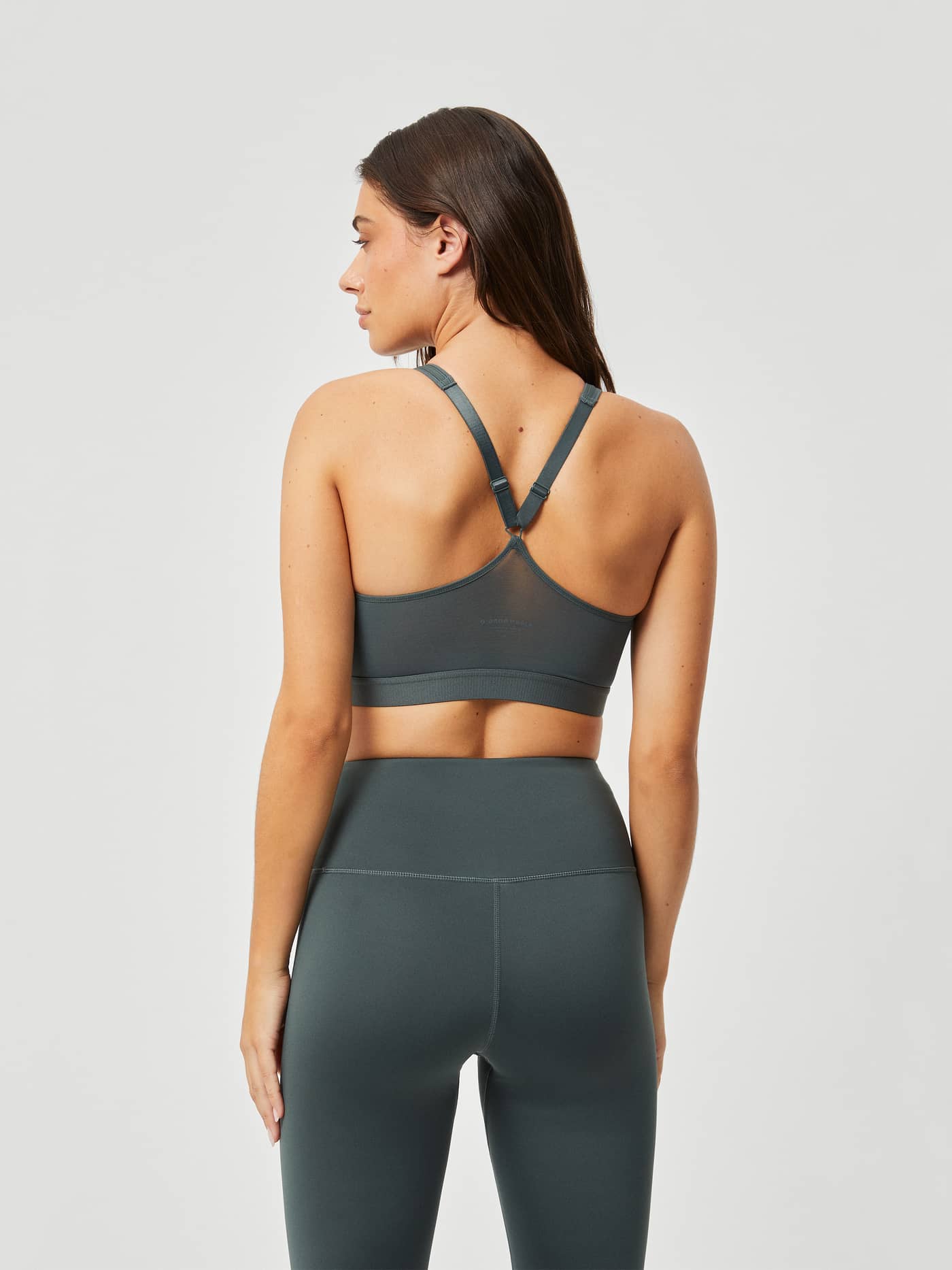 Back view of a woman wearing the Borg Mid V Support in Green, featuring a breathable mesh panel and a stylish training fit. - Image 2