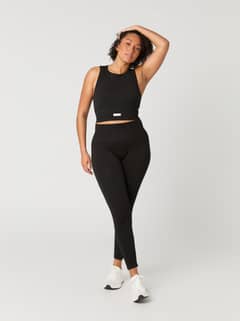 Full-body front view of a woman wearing the rib-knitted Studio Seamless Bralette in Black Beauty (Black) for training. - Image 1