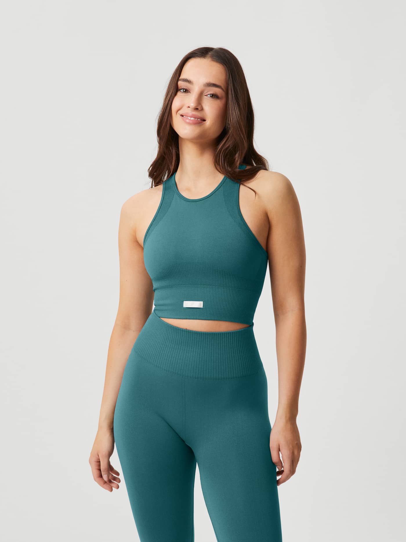 Front view of a woman wearing the slim fit rib-knitted Studio Seamless Bralette in Blue with a white logo for training. - Image 2