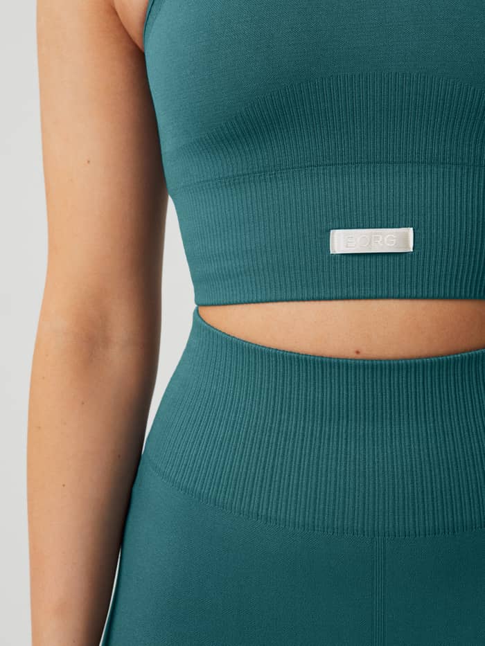 Nahaufnahme des Studio Seamless Bralette in Mallard Blue (Blau) mit weißem BORG-Logo und gerippter Trainingspassform. - Image 5