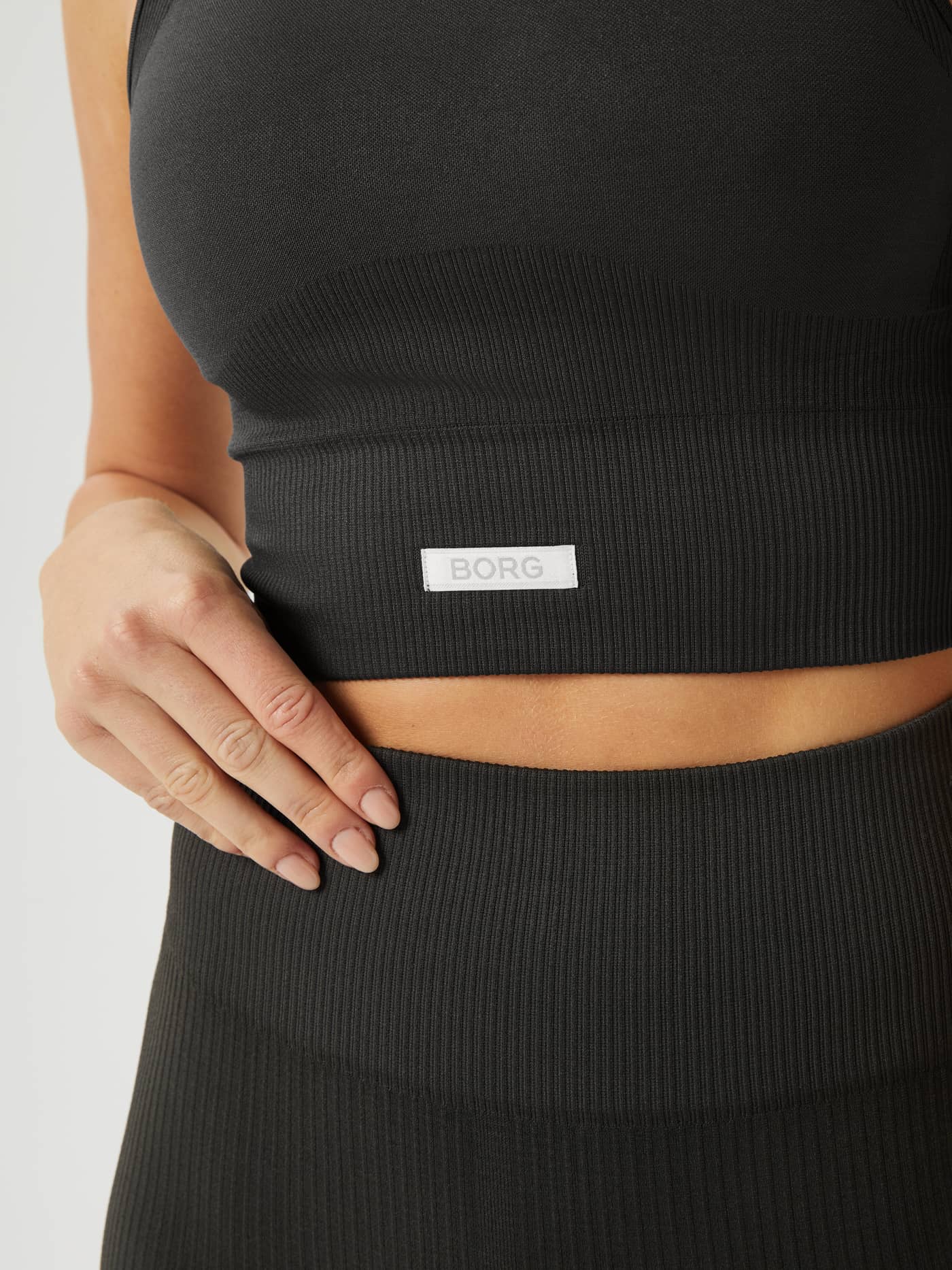 Närbild på ribbstickad Studio Seamless Bralette i Peat (Grön) för träning med en vit BORG-logotyp. - Image 5