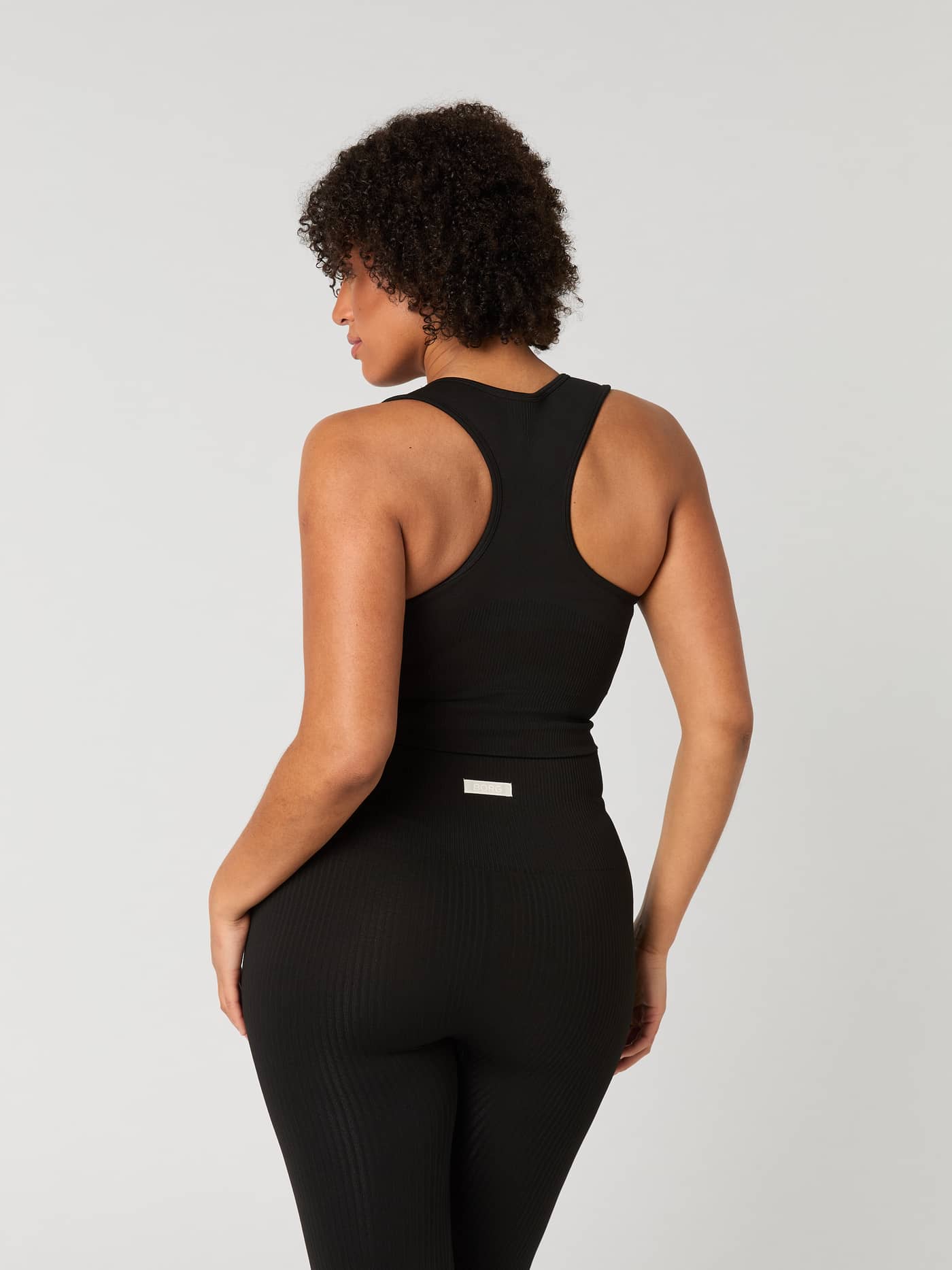 Back view of a woman wearing the black Studio Seamless Bralette with a rib-knitted racerback design for training. - Image 3
