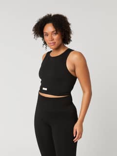 Rib-knitted Studio Seamless Bralette in Black Beauty (Black) with a white logo, styled on a woman for training. - Image 2