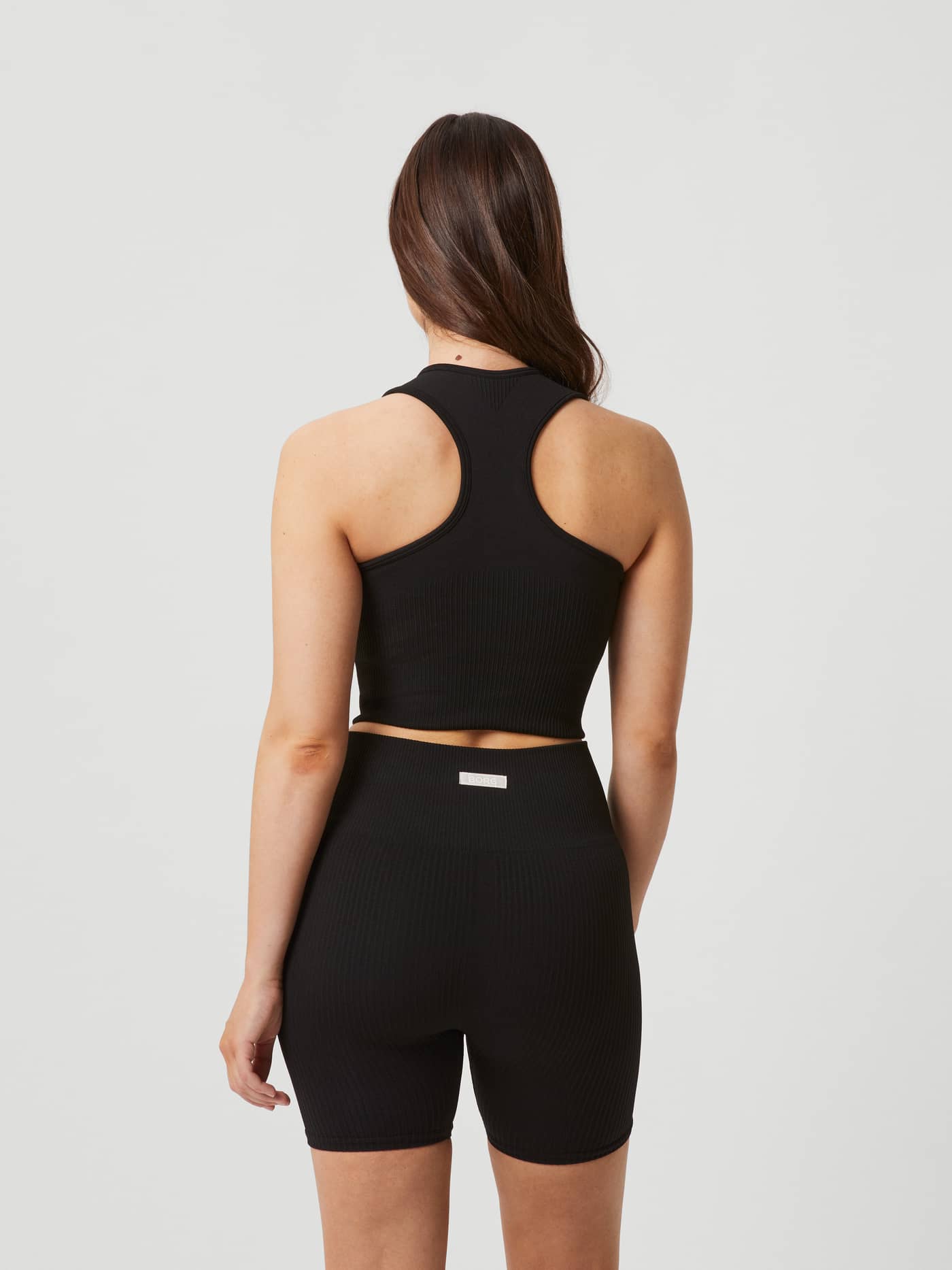 Back view of a woman wearing the black Björn Borg Studio Seamless Bralette with a rib-knitted racerback for training. - Image 5