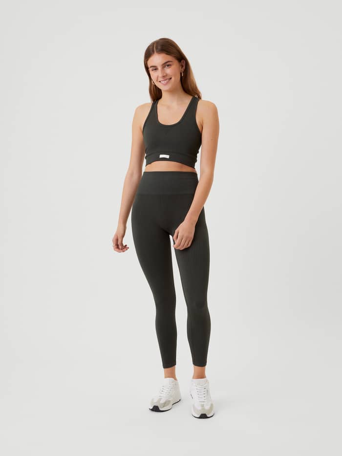 Ganzkörper-Vorderansicht einer Frau im Studio Low Seamless Bra in Peat (Grün) mit weißem Logo und Training-Leggings. - Image 5