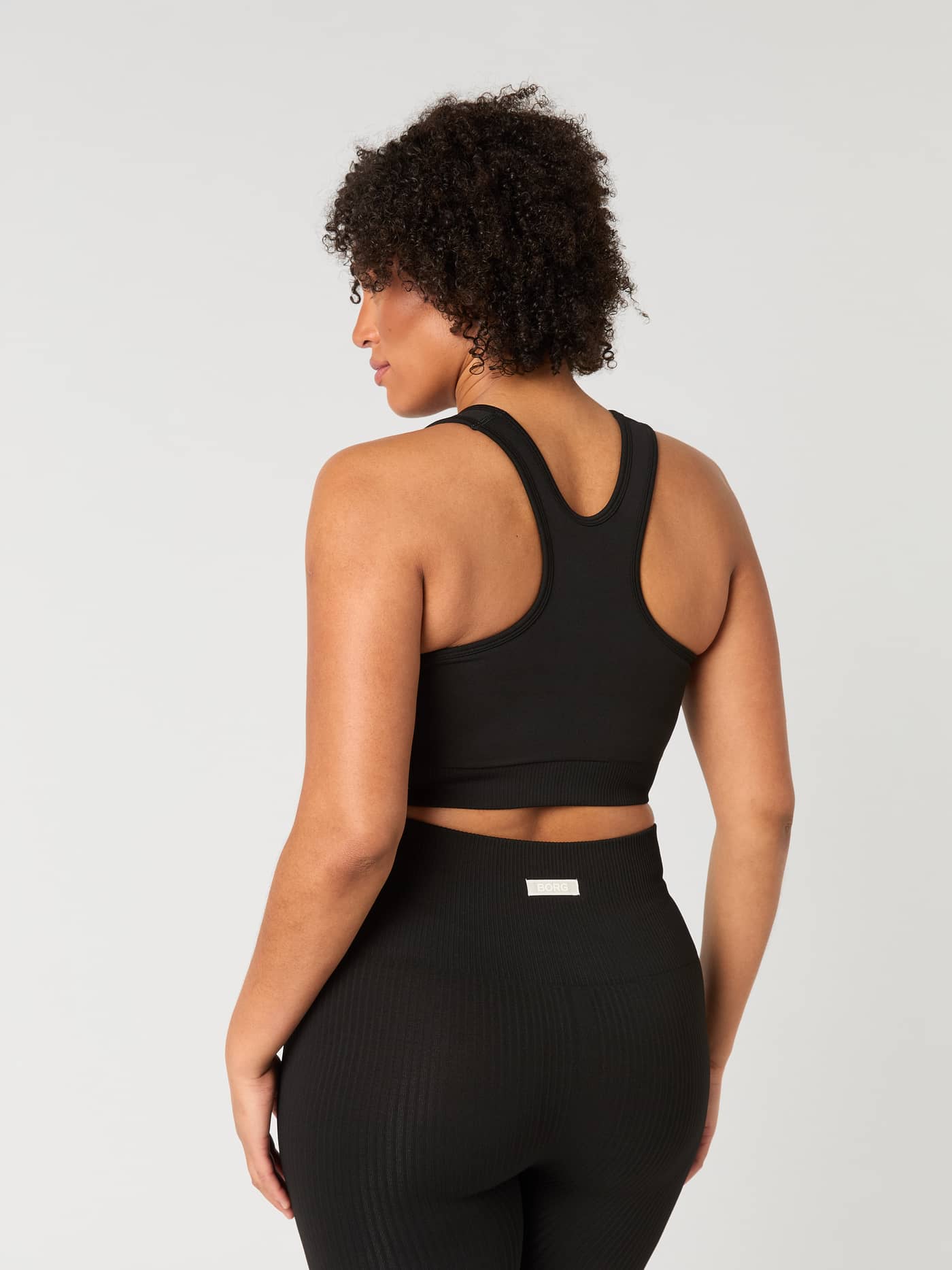 Vue arrière d'une femme portant le Studio Low Seamless Bra en Black Beauty (Noir) avec un dos nageur pour le training. - Image 5